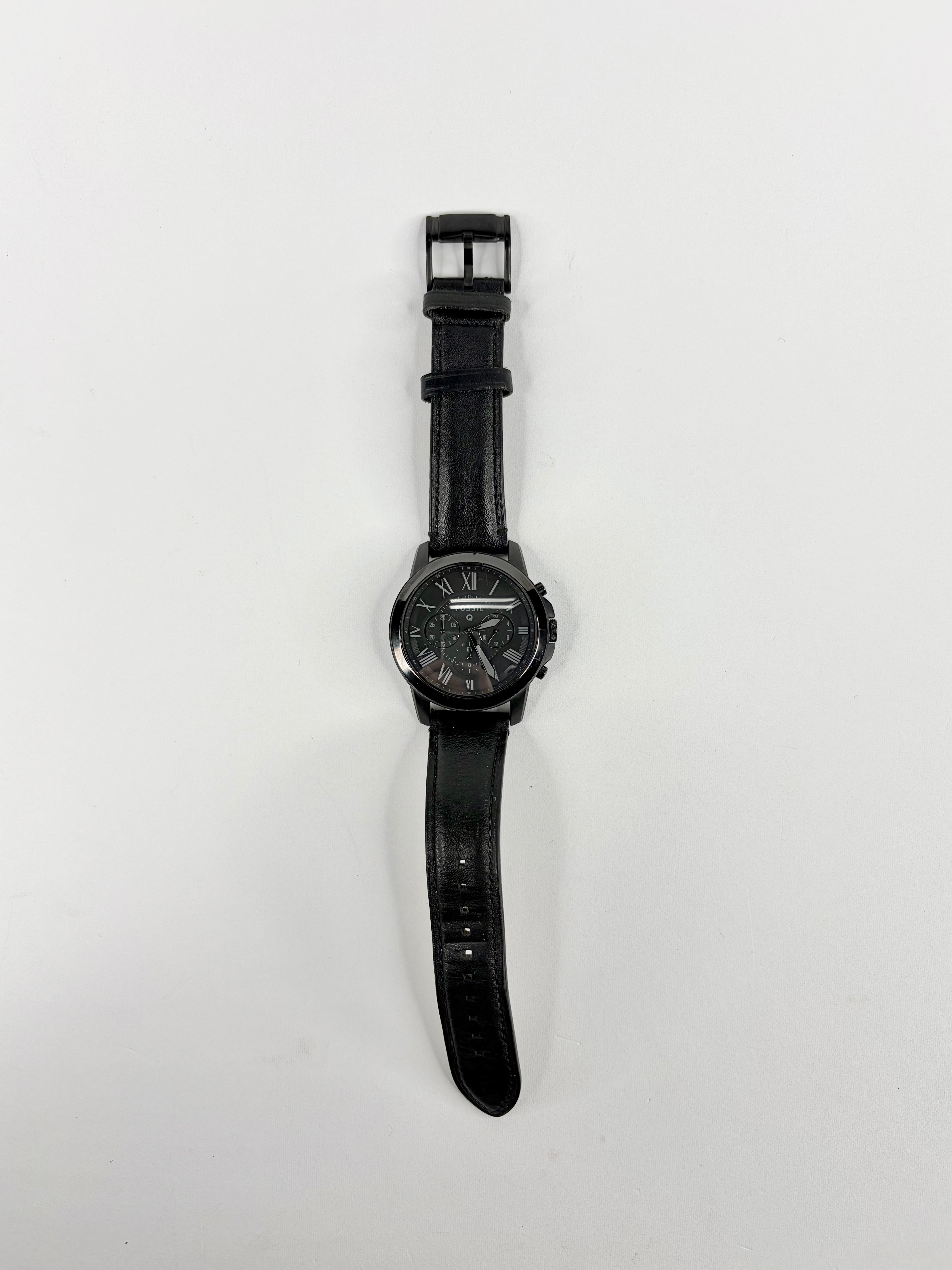 Black wristwatch with leather strap on a white background