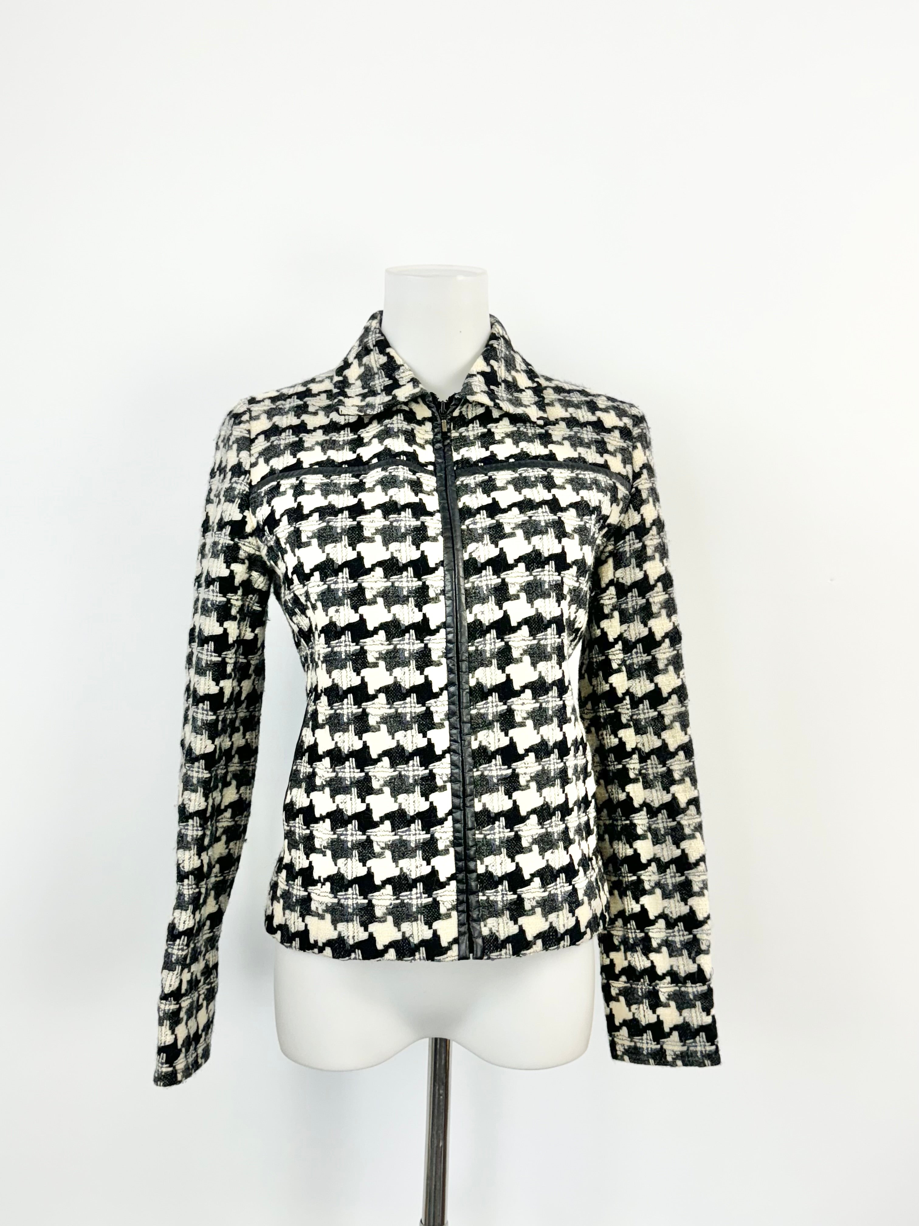 A black and cream wool woven houndstooth pattern jacket displayed on a mannequin with a zipper and without a collar.