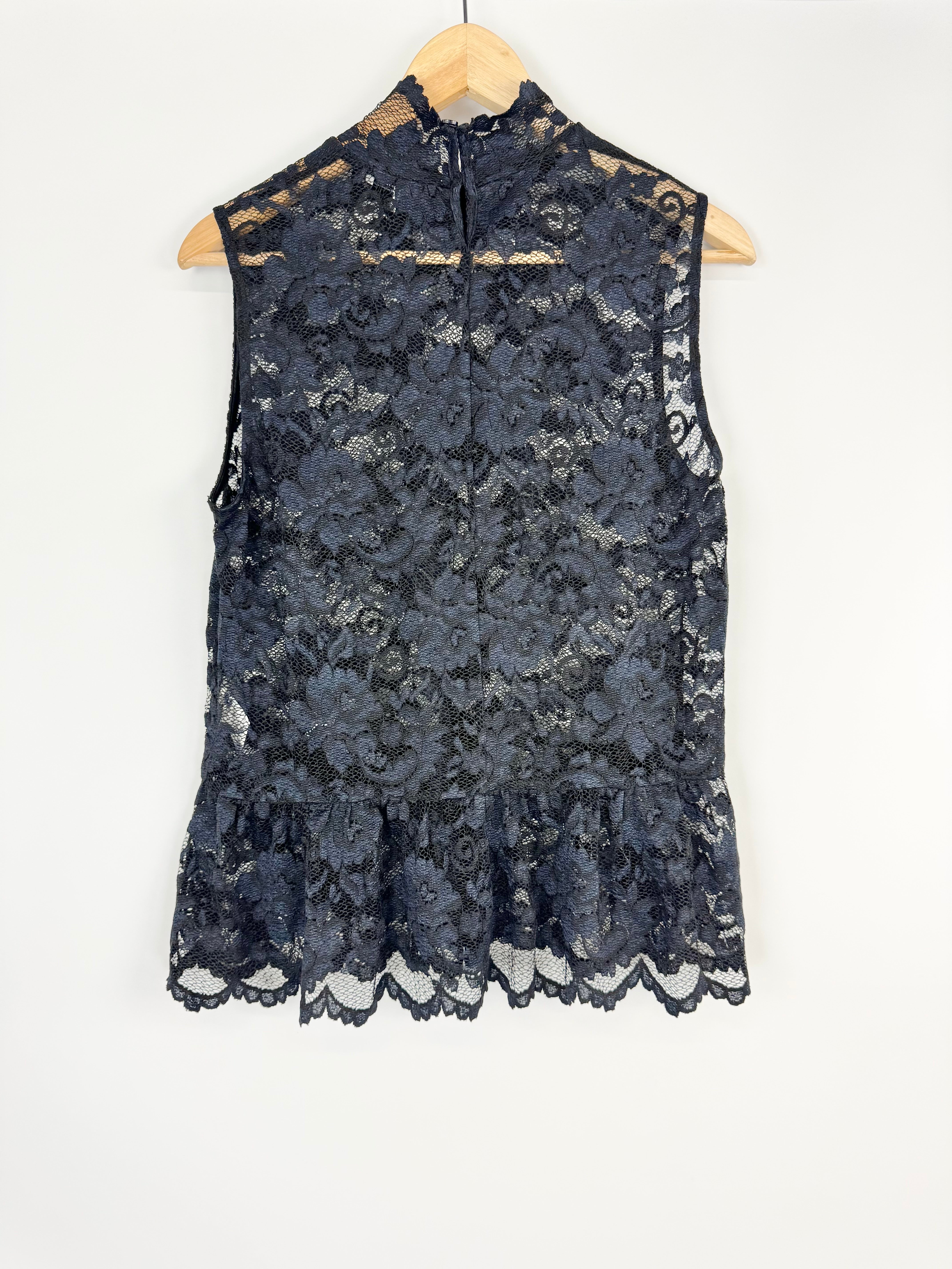Black lace sleeveless top on a wooden hanger against a white background