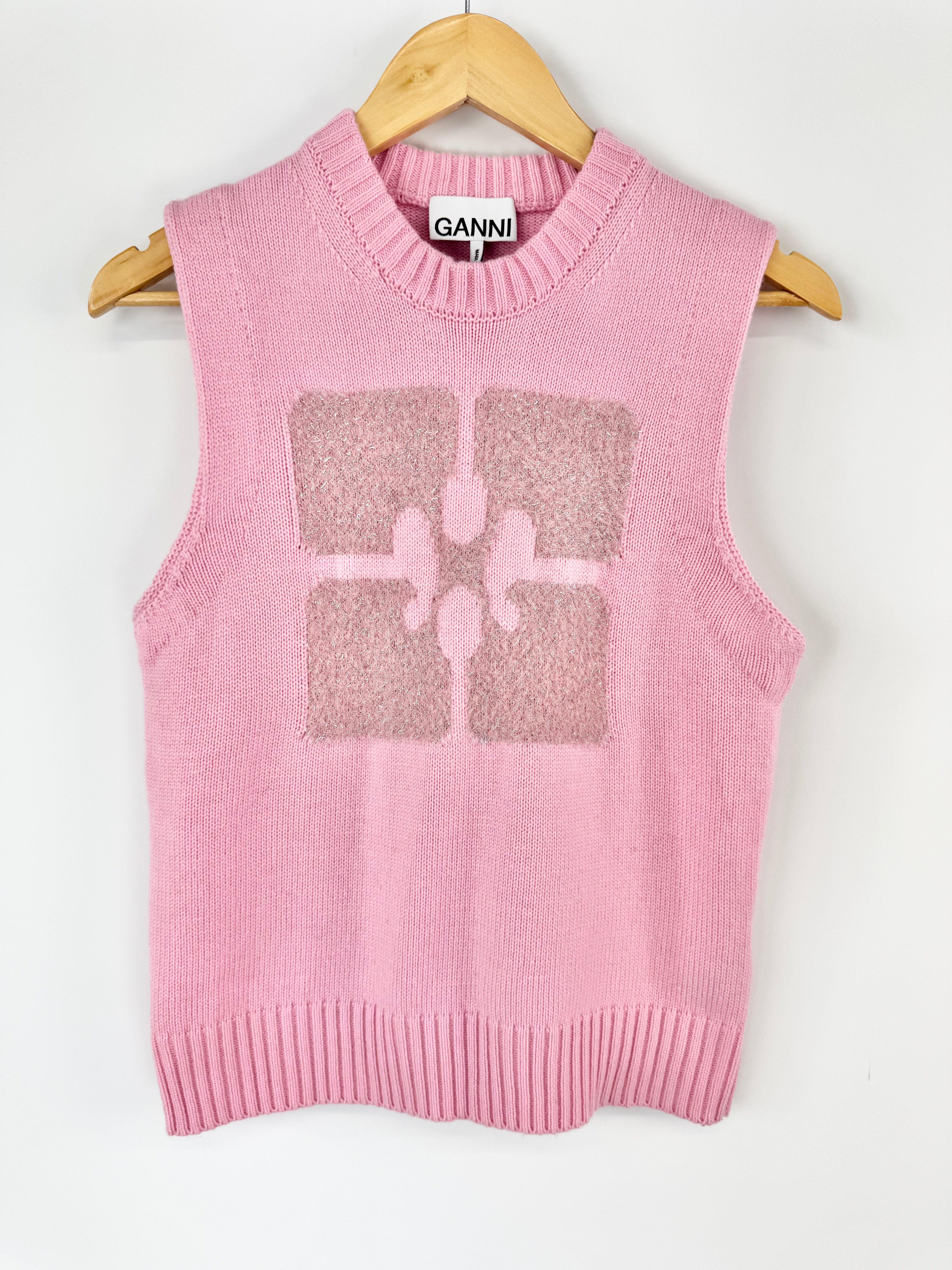 Pink sleeveless sweater vest with a glittery design on a hanger against a white background