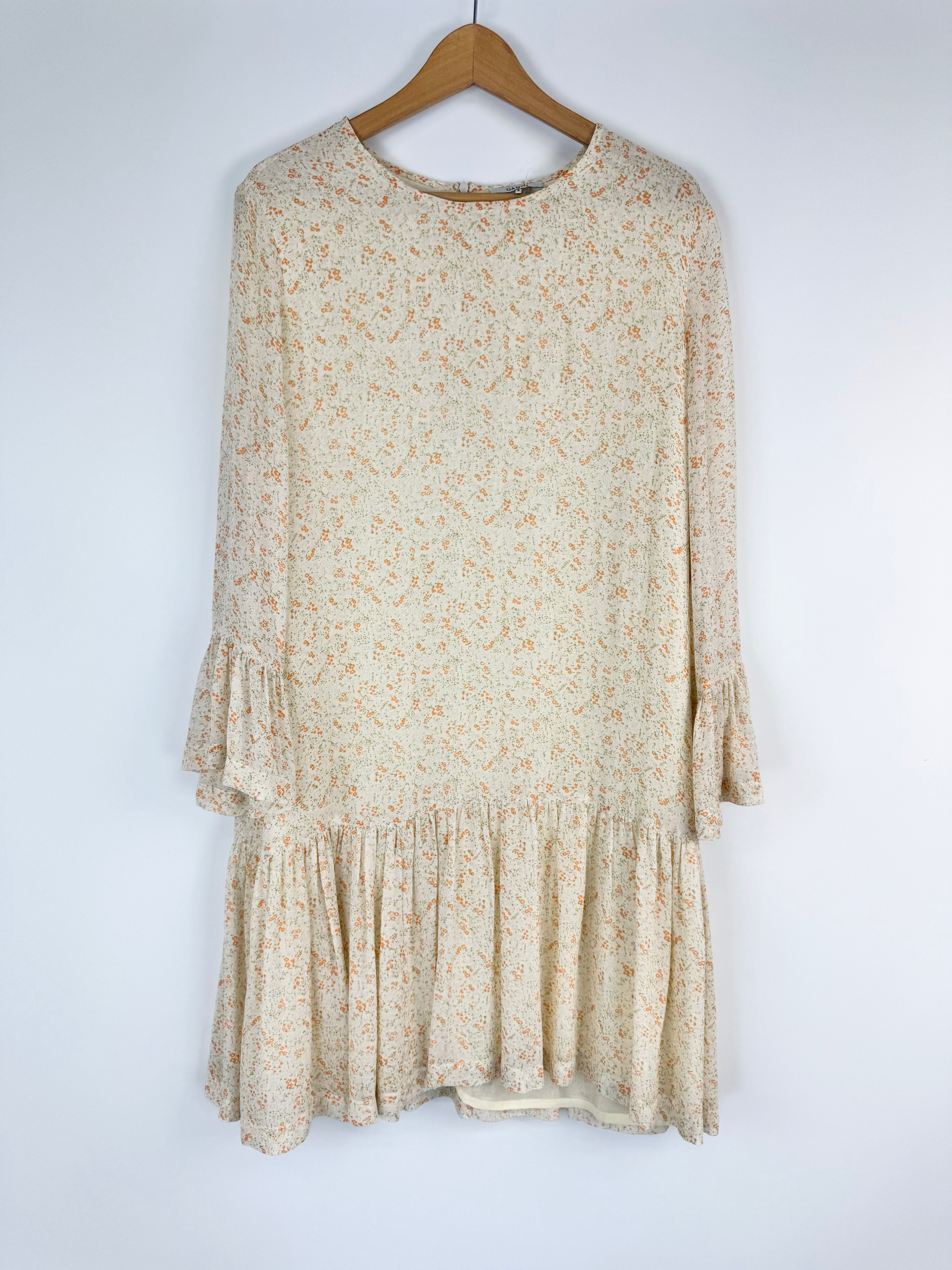 Beige floral dress on a wooden hanger against a white background