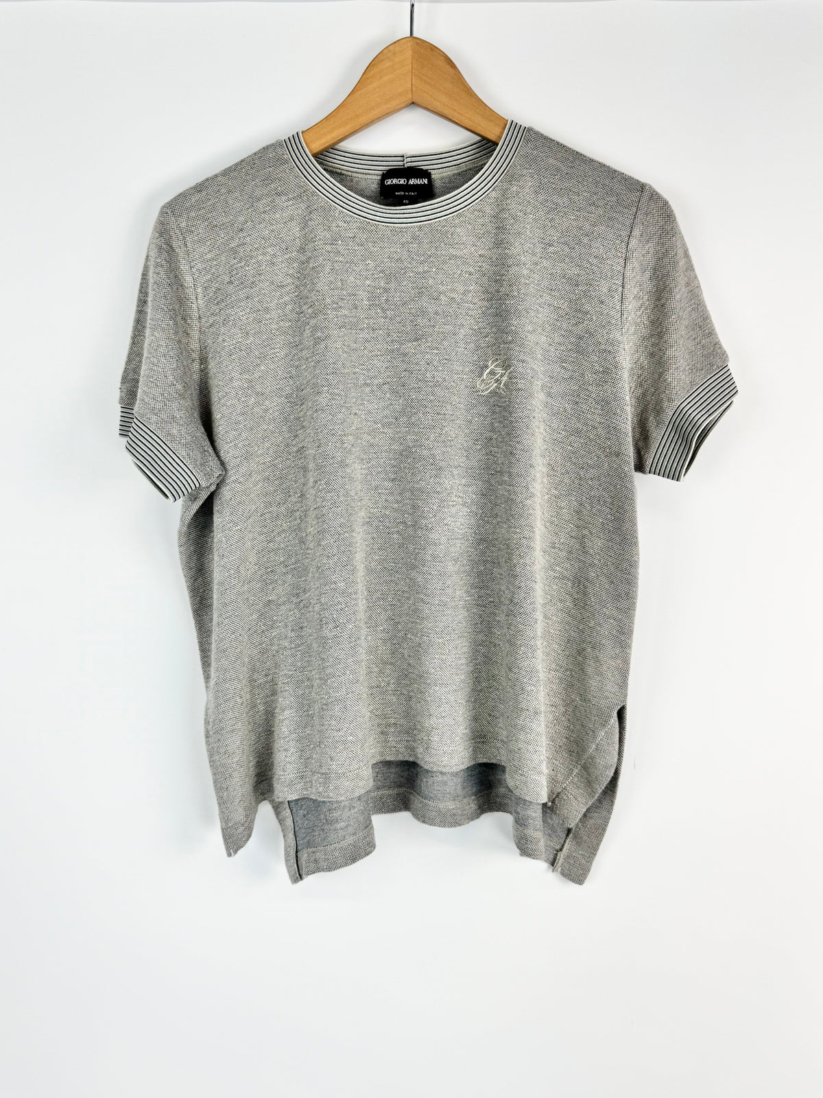 Gray T-shirt with a small logo on a wooden hanger against a white background
