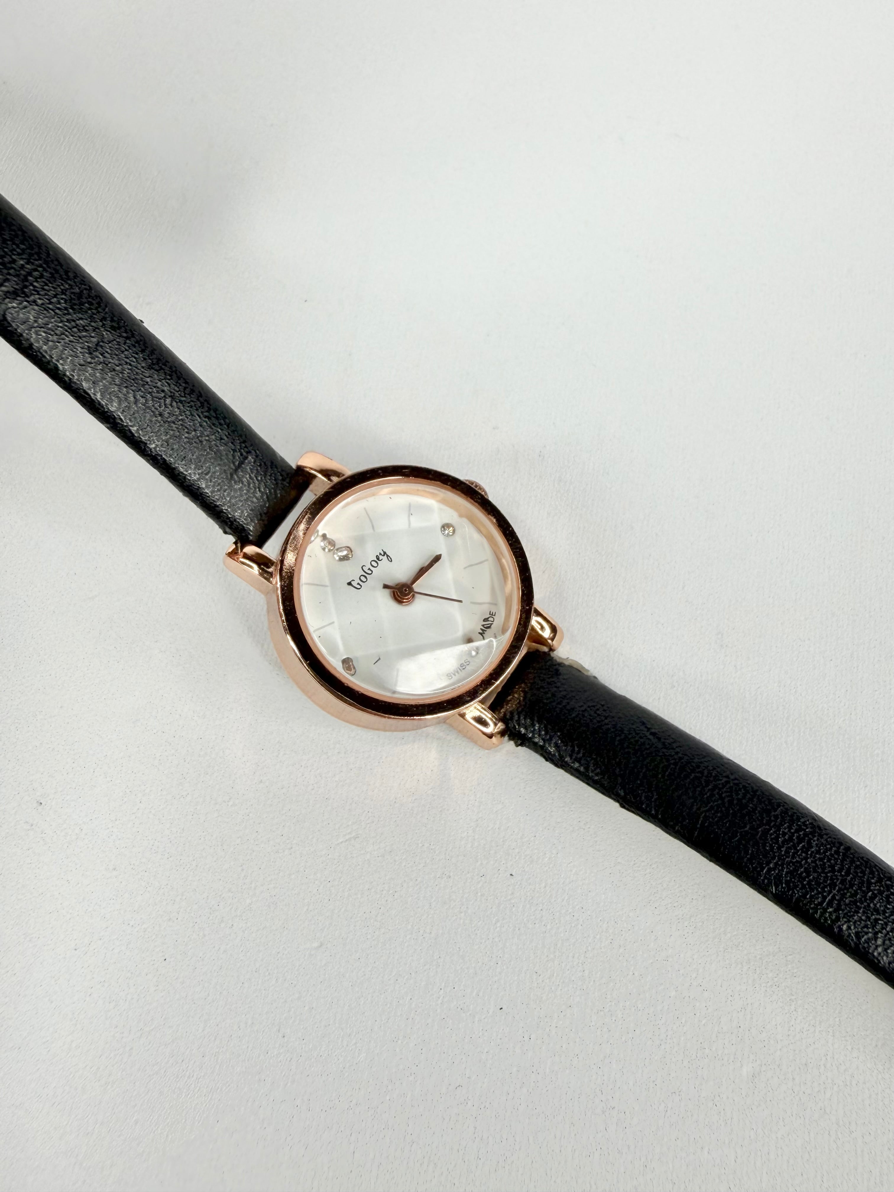 Wristwatch with black strap and rose gold case on a light gray background