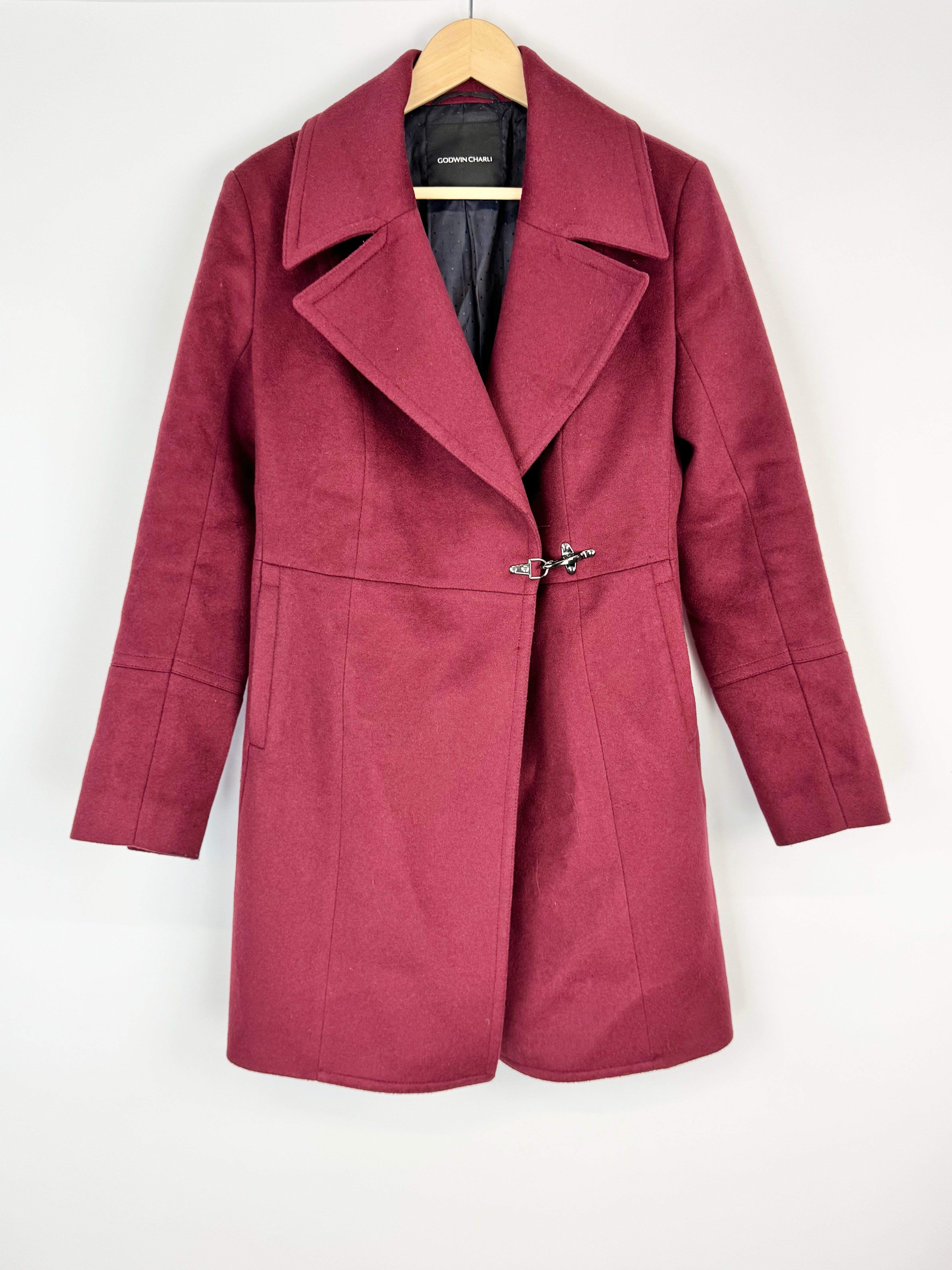 Maroon coat on a hanger against a white background