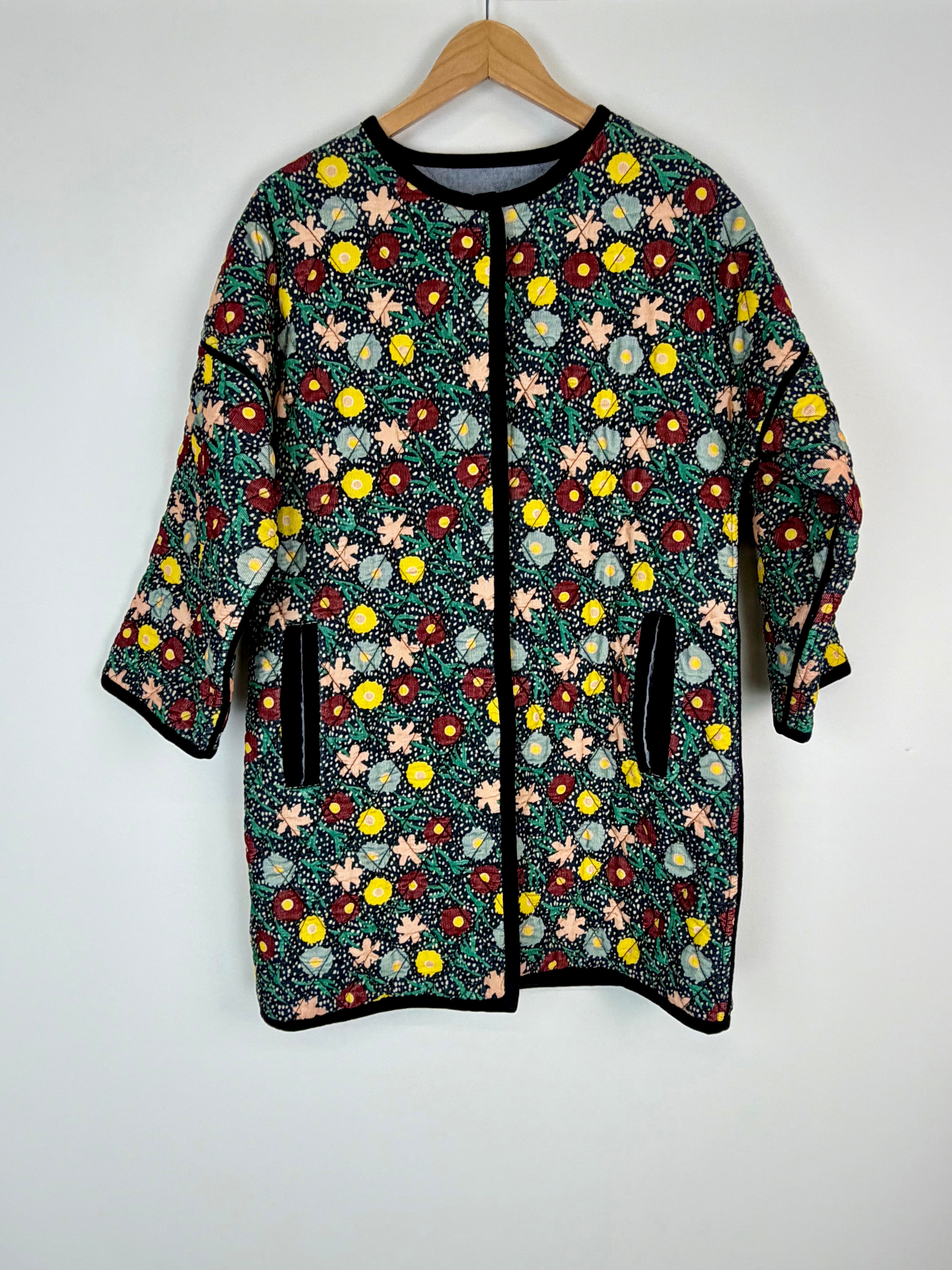 Floral patterned jacket on a hanger against a white background