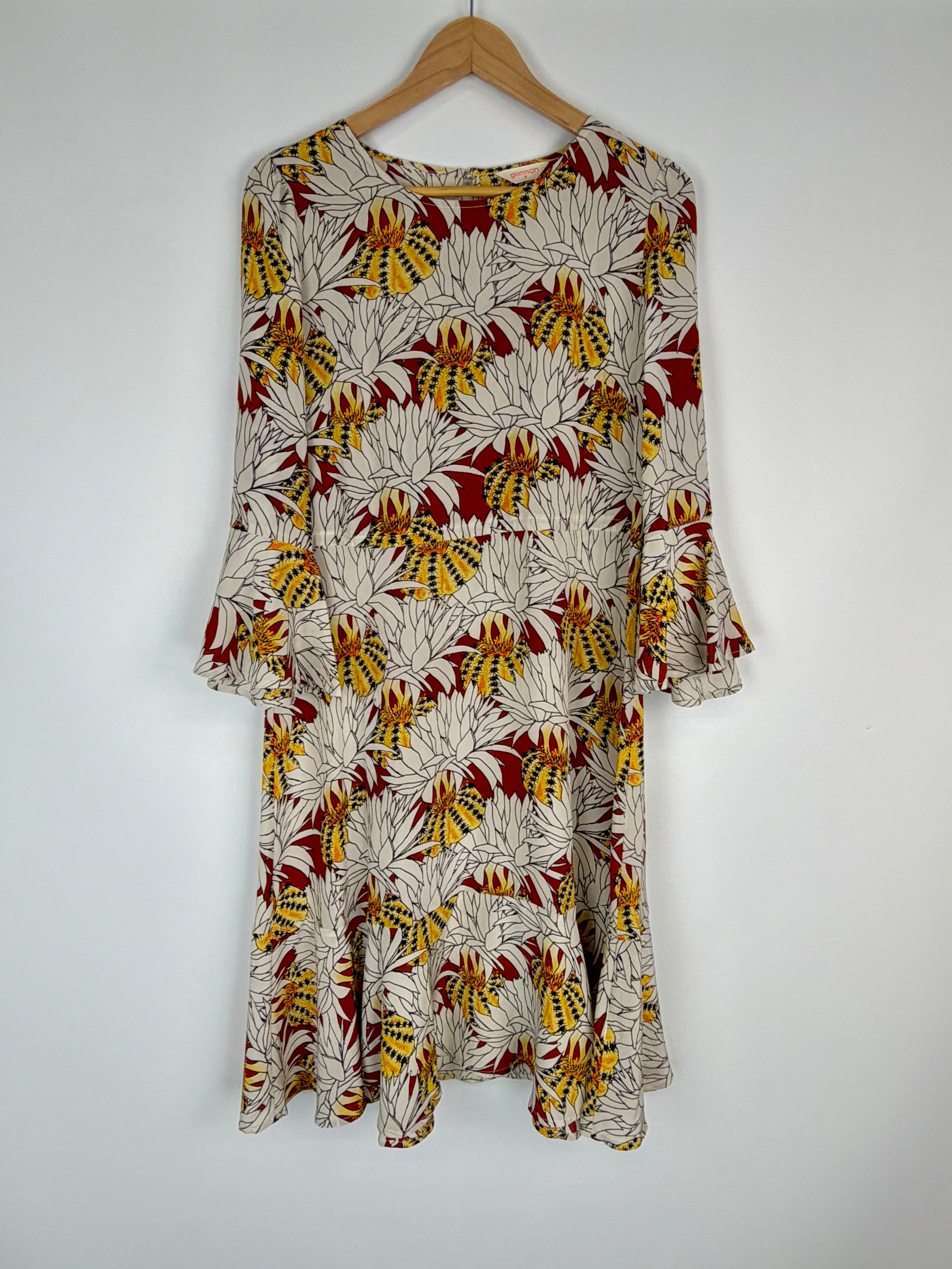 Floral patterned dress on a wooden hanger against a white background