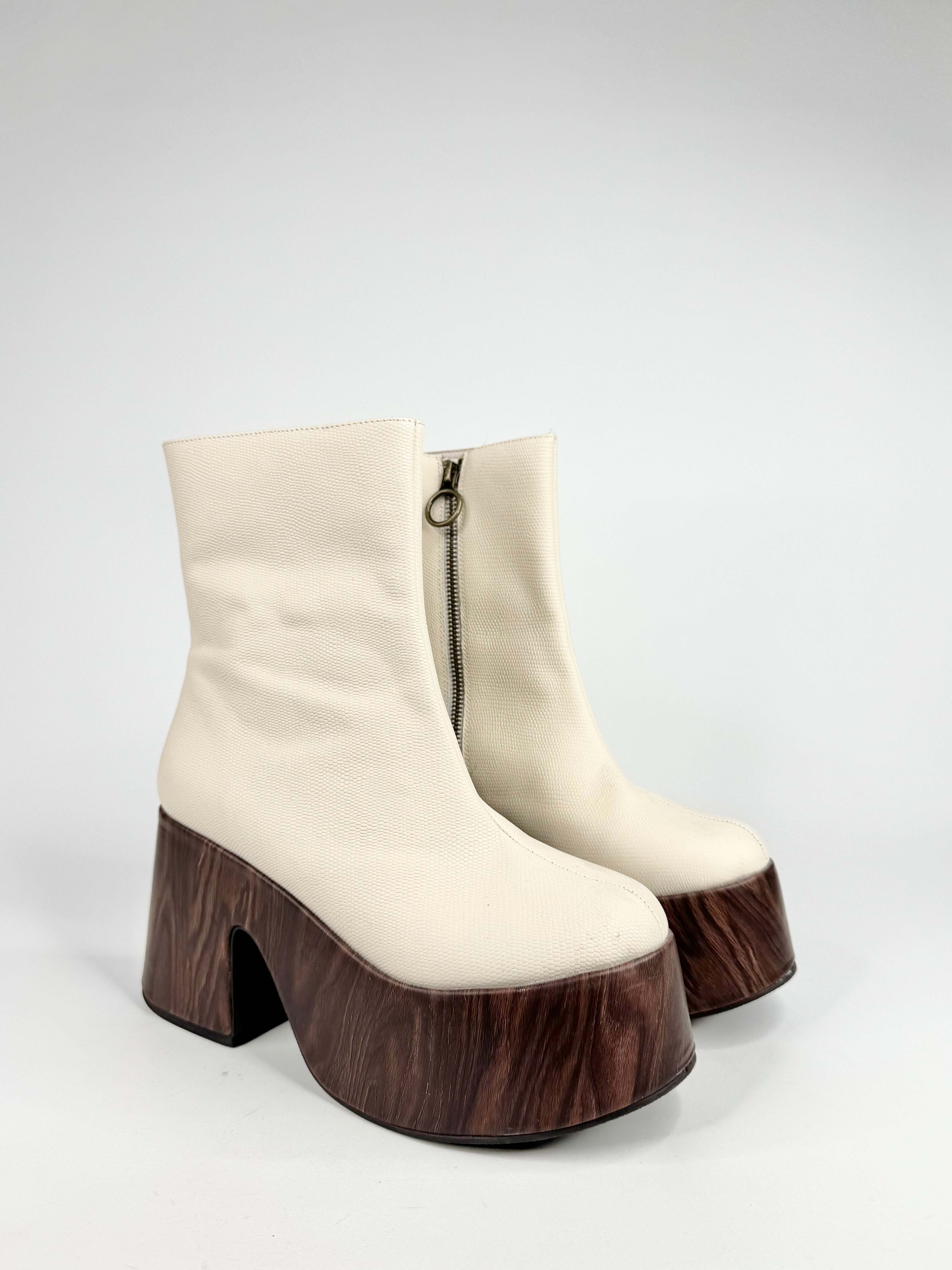 White ankle boots with brown platform soles on a light gray background
