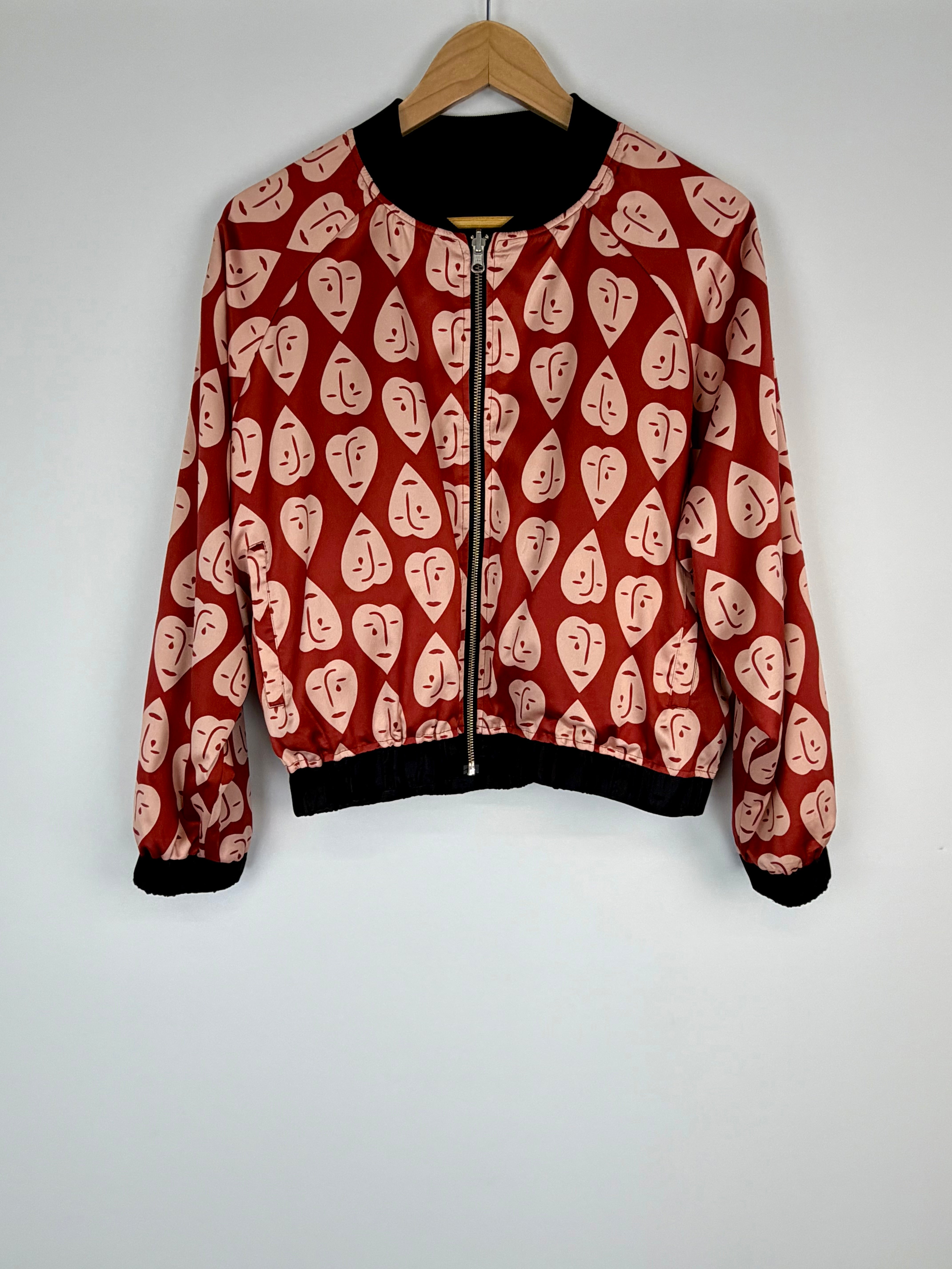 Red jacket with face pattern on a hanger against a white background