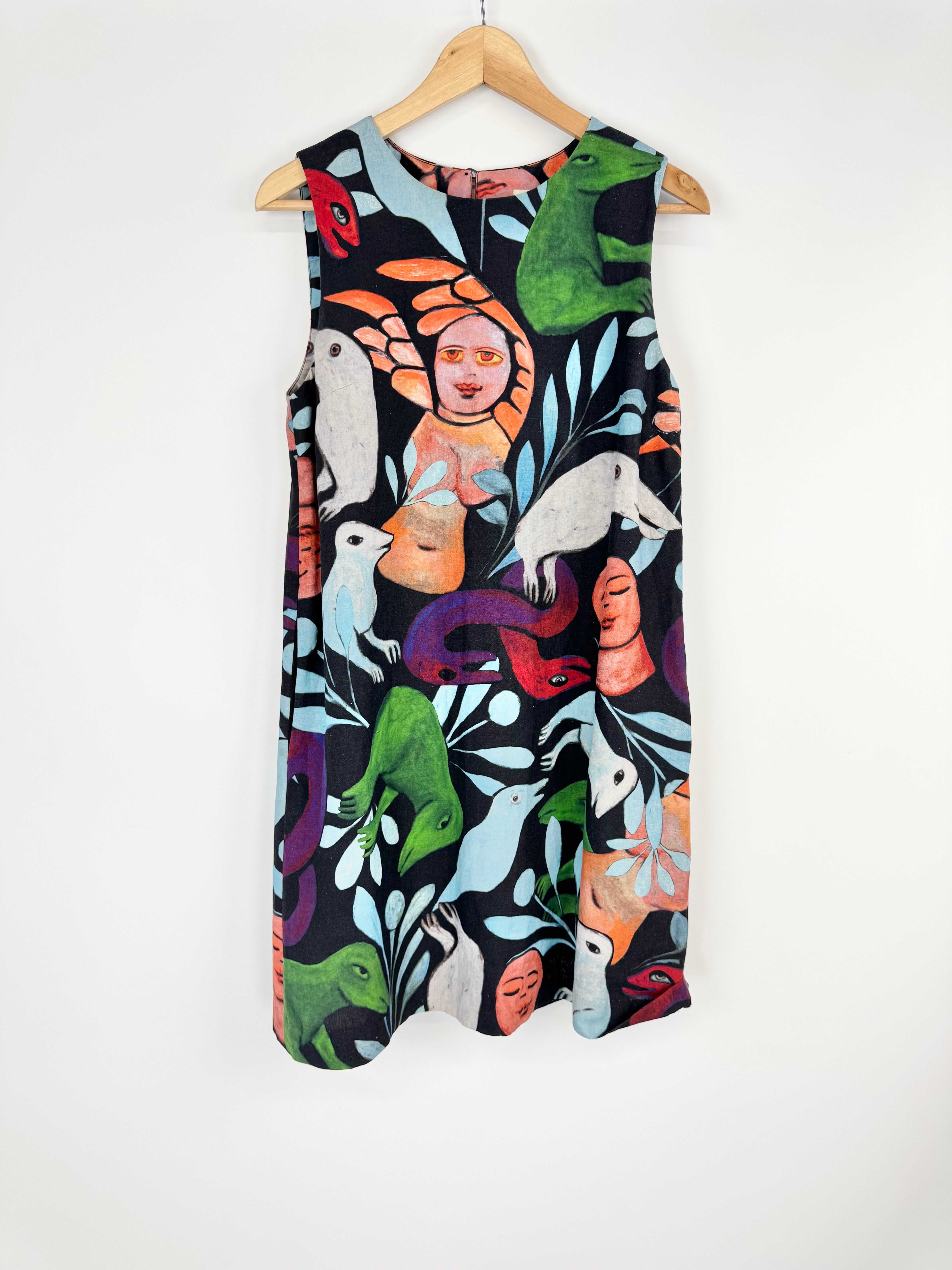 Colorful sleeveless dress with animal and abstract design on a hanger against a white background