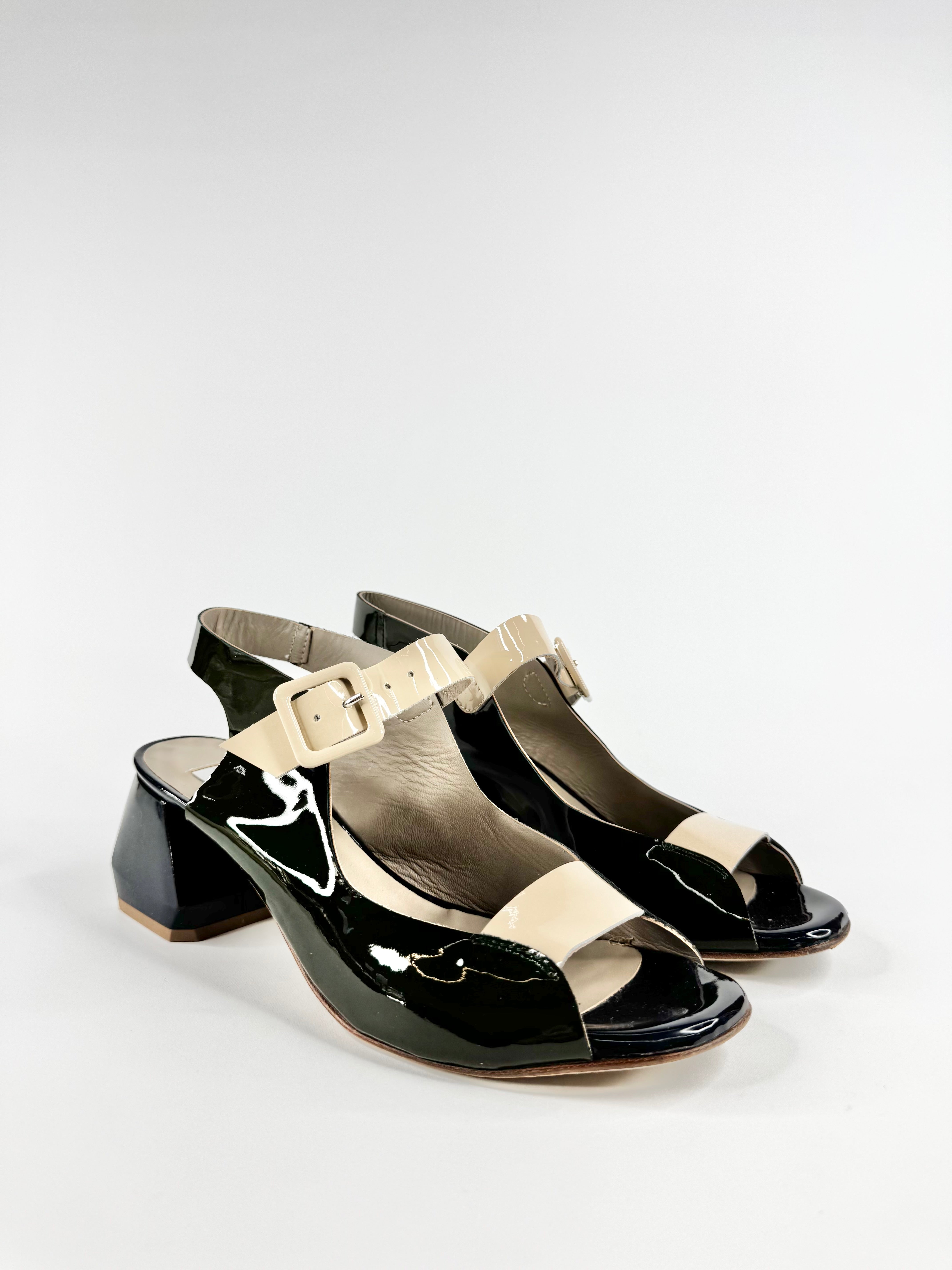 Black patent leather sandals with beige straps on a white background