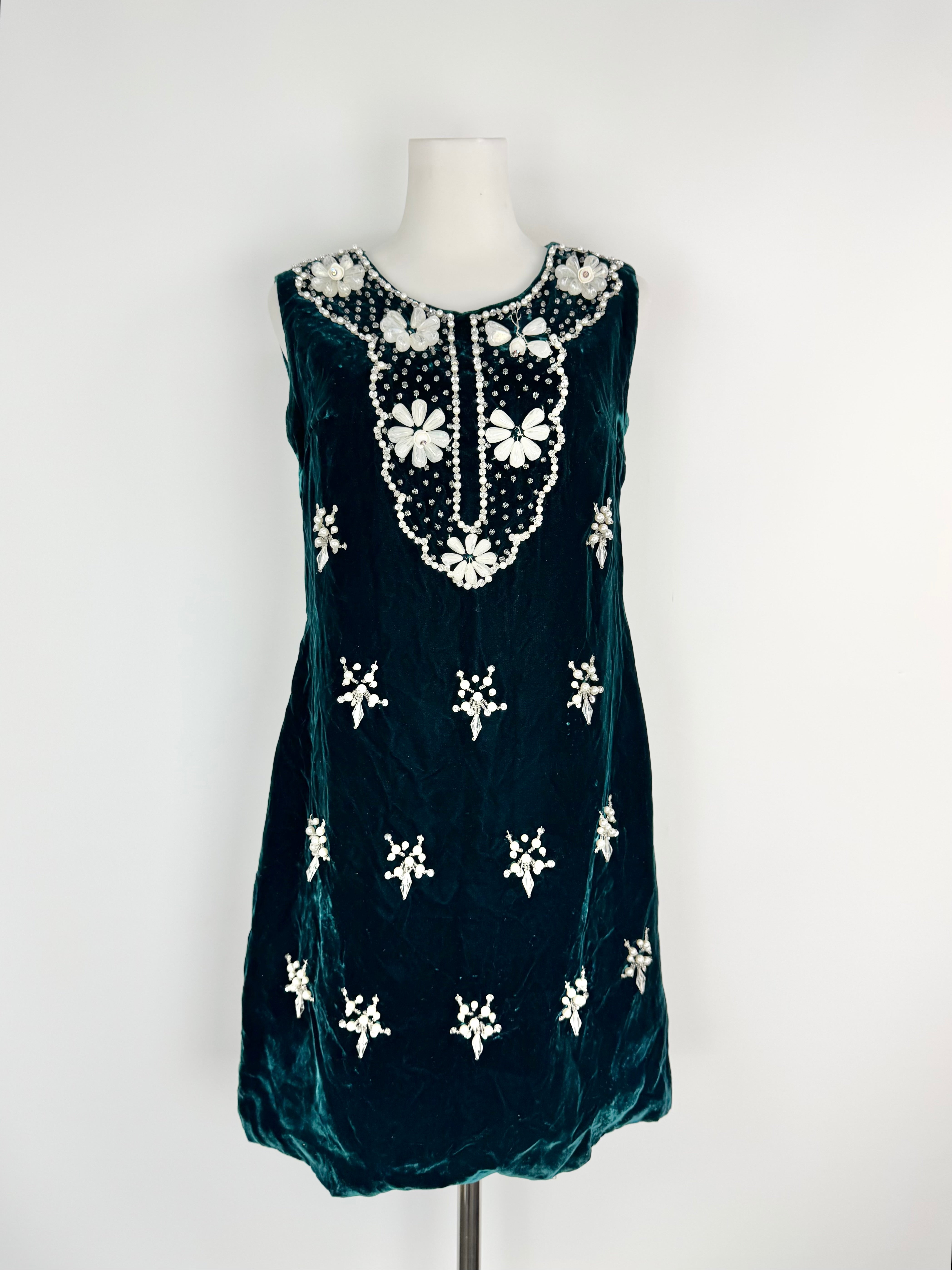 Dark green dress with white floral embroidery on a mannequin against a white background