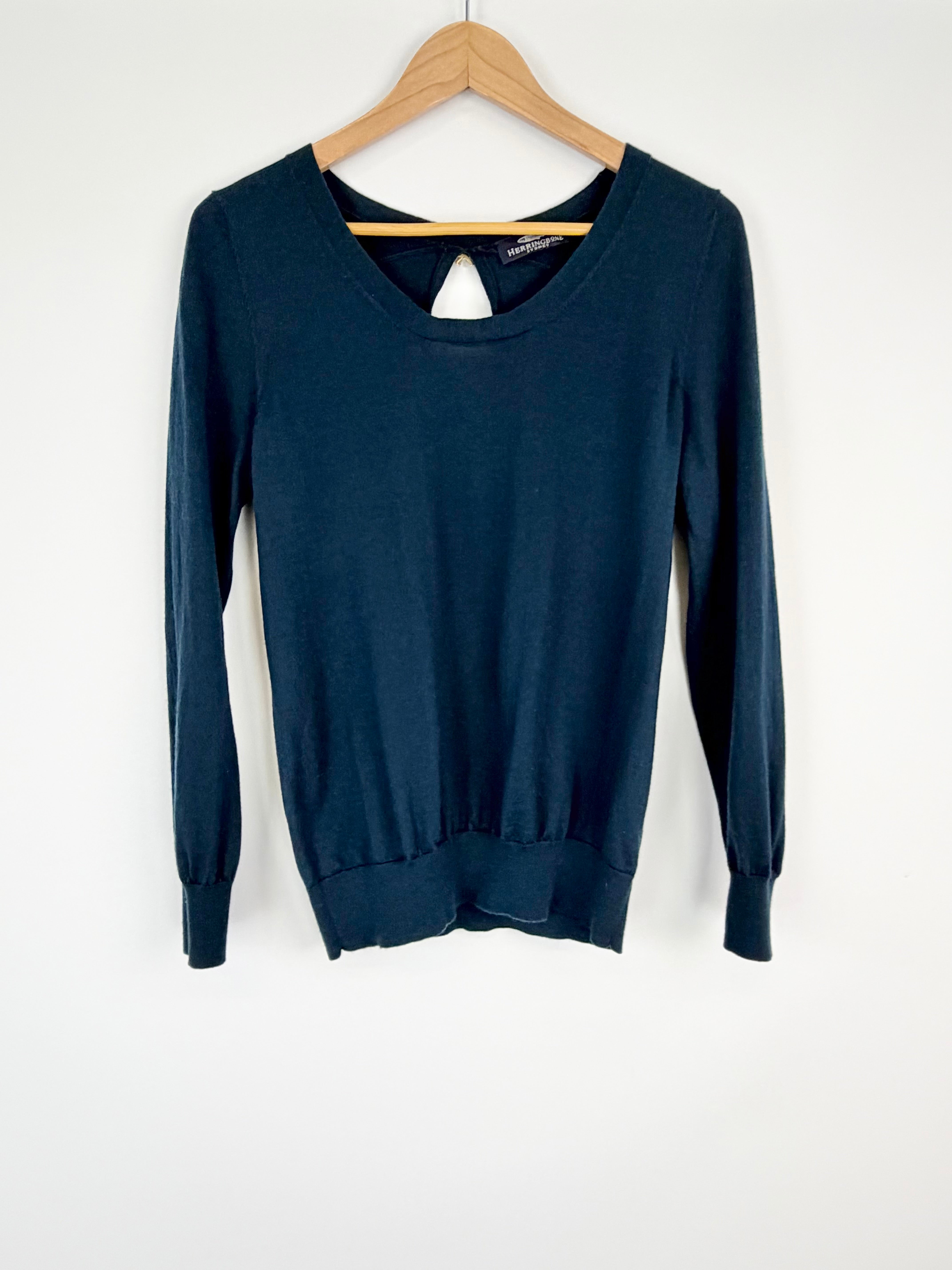 Blue sweater on a wooden hanger against a white background