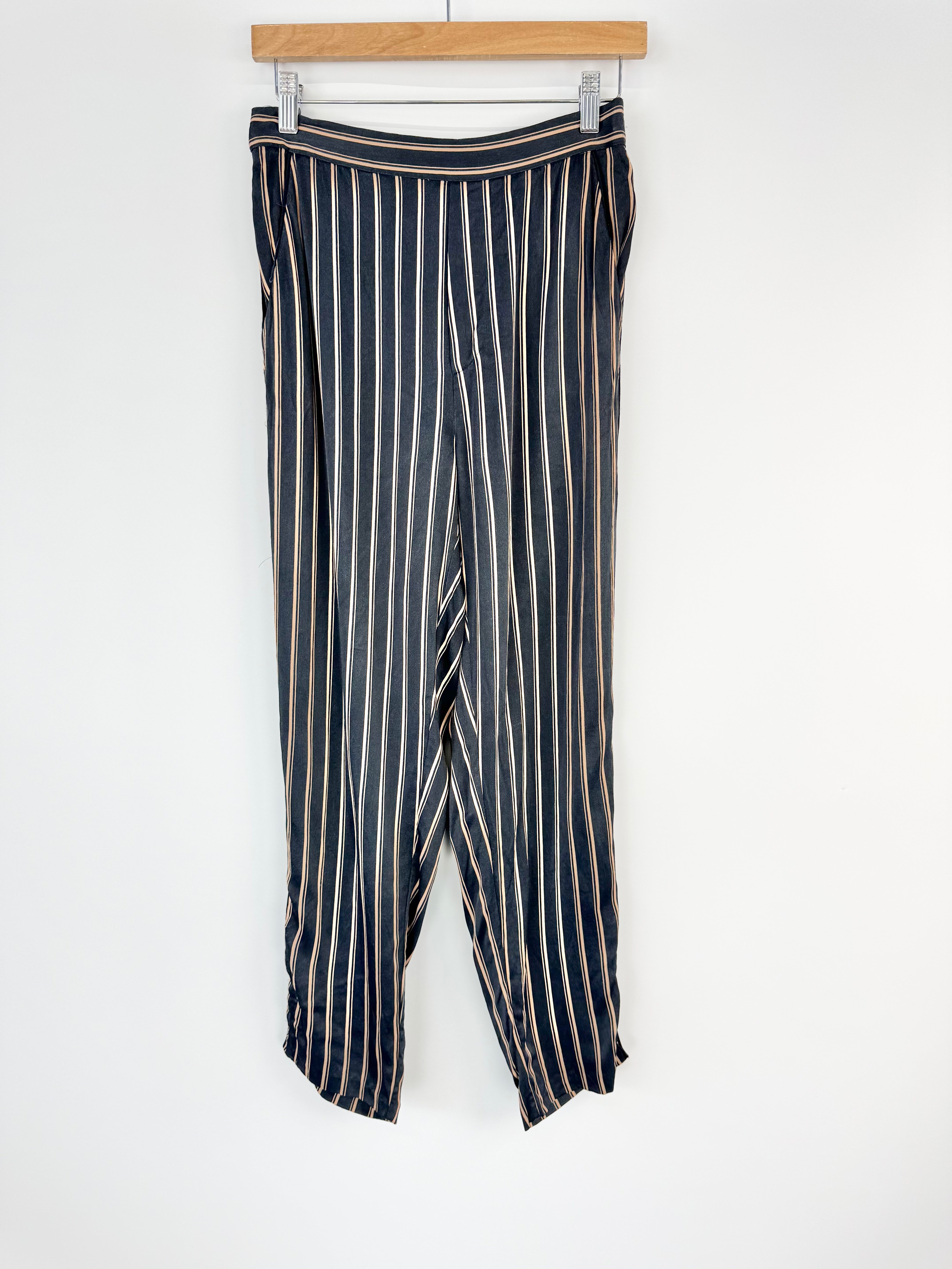 Striped pants hanging on a wooden hanger against a white background