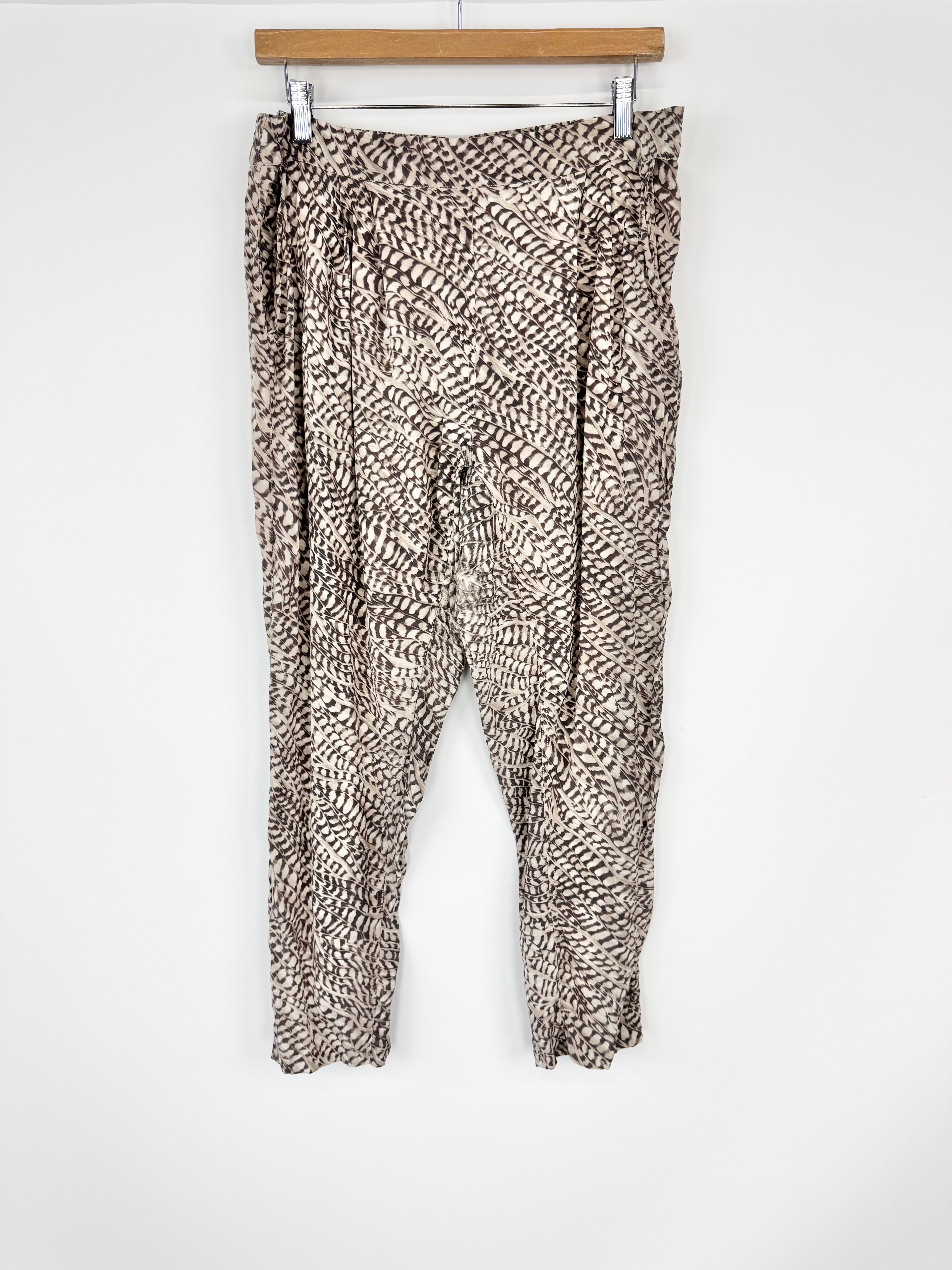 Leopard print pants hanging on a wooden hanger against a white background