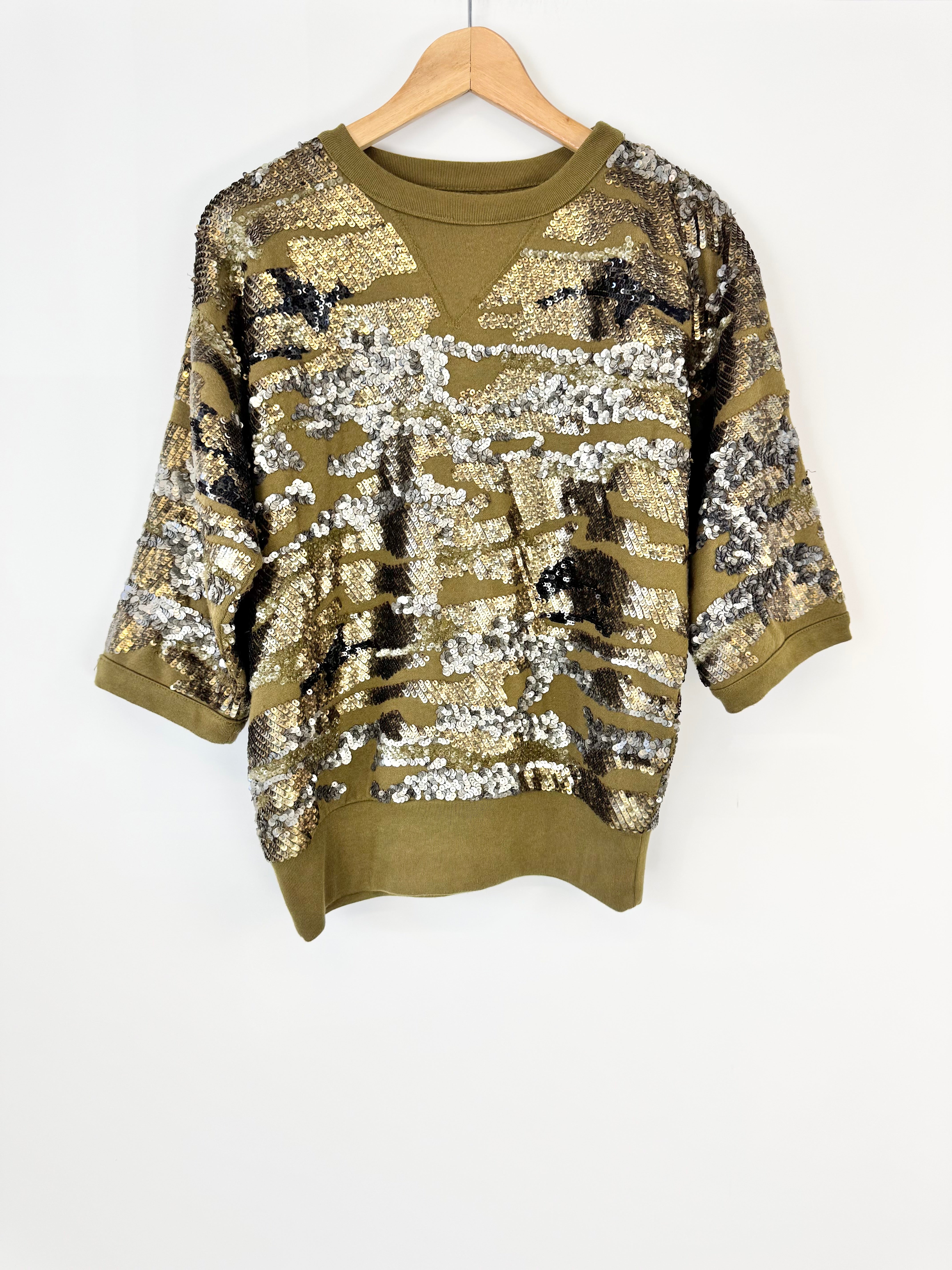 Green sweater with sequin pattern on a hanger against a white background