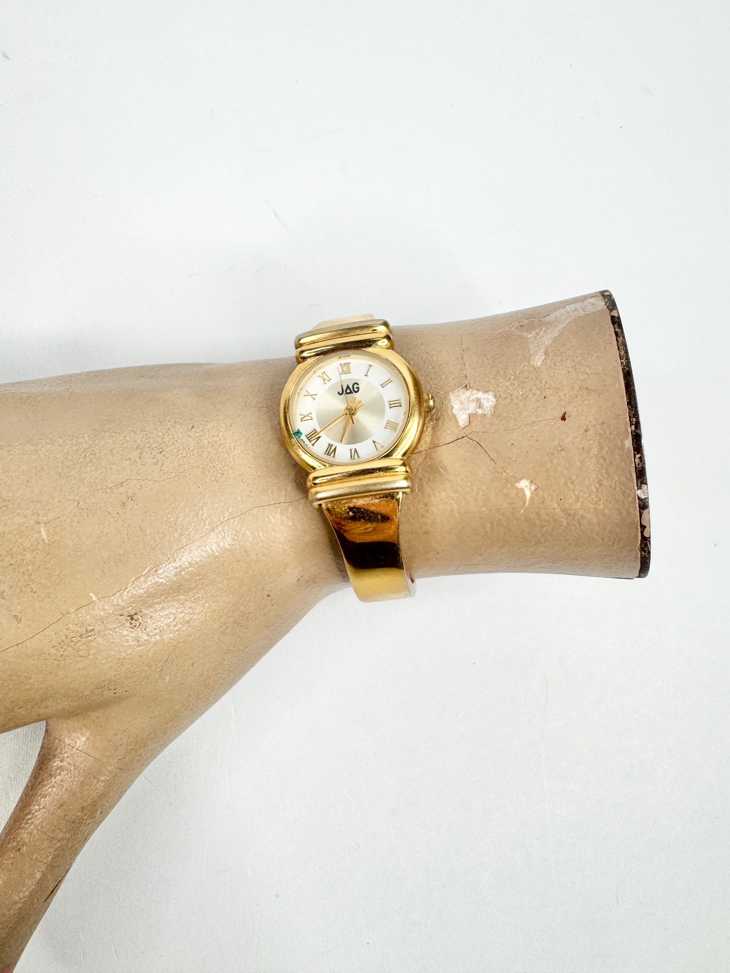 Gold watch on a mannequin arm against a white background