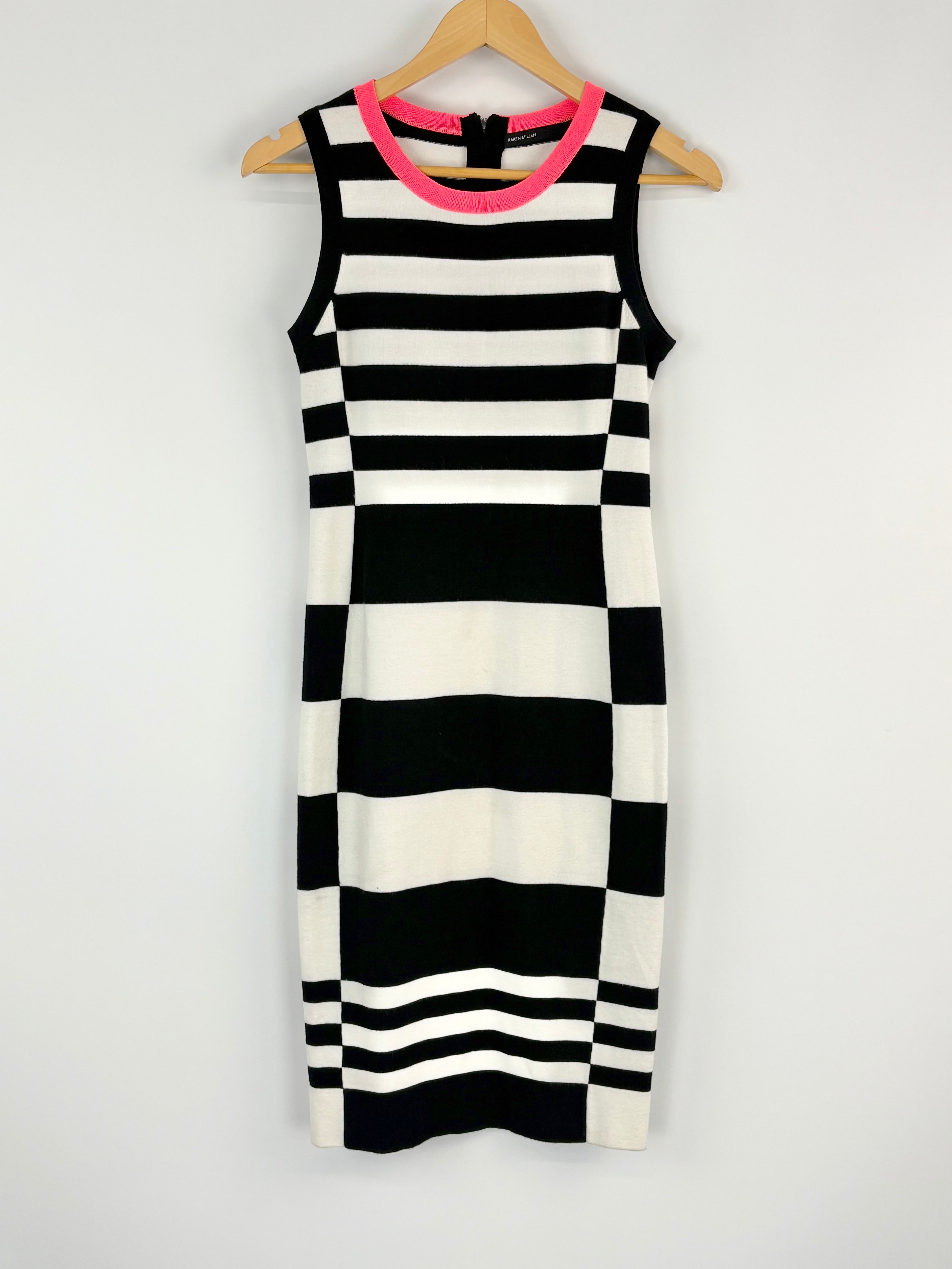 Black and white striped dress with pink trim on a hanger against a white background