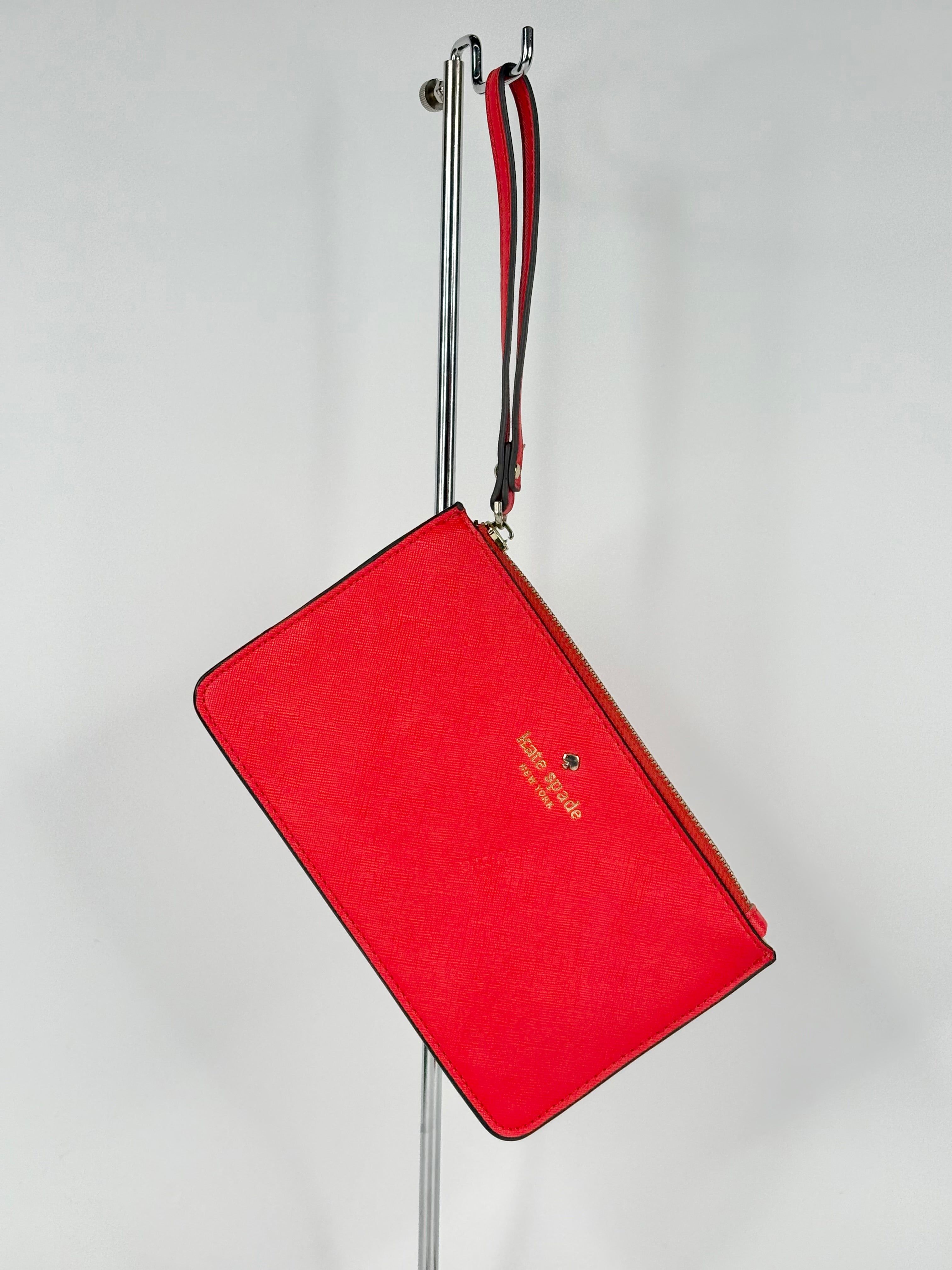 Red clutch bag with a strap on a gray background