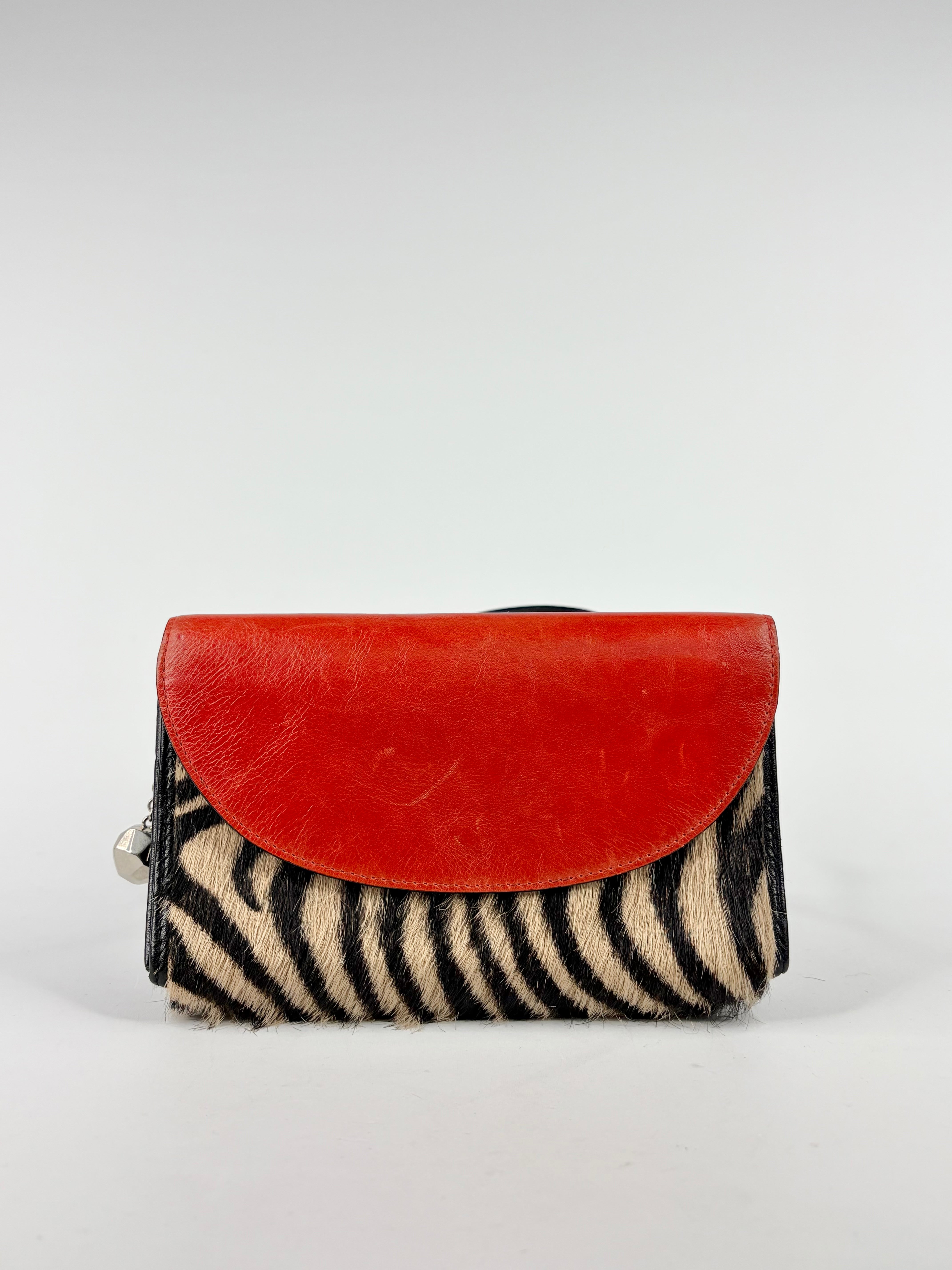 Handbag with red top flap and zebra-striped bottom on a white background