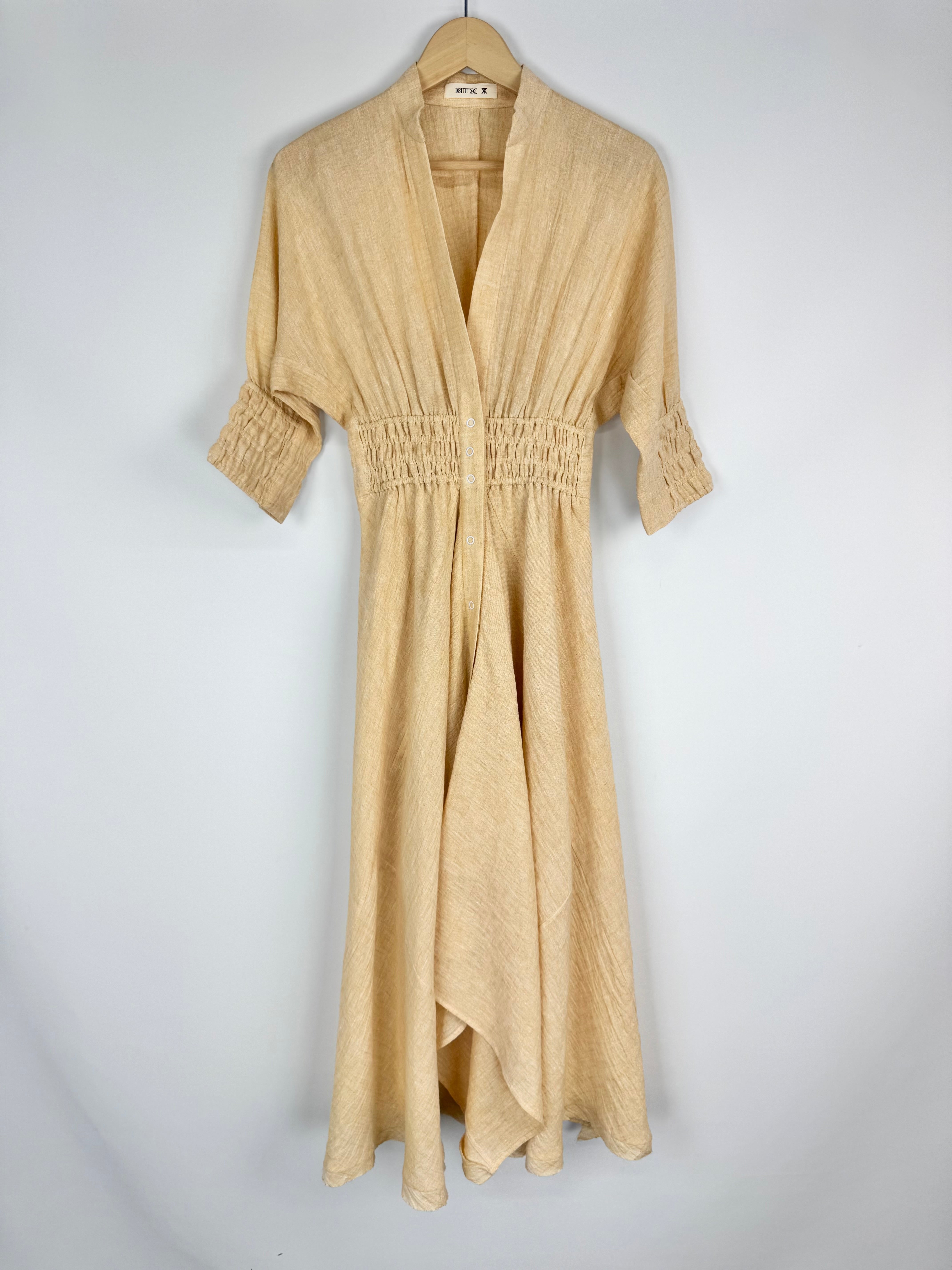 Beige dress on a hanger against a white background