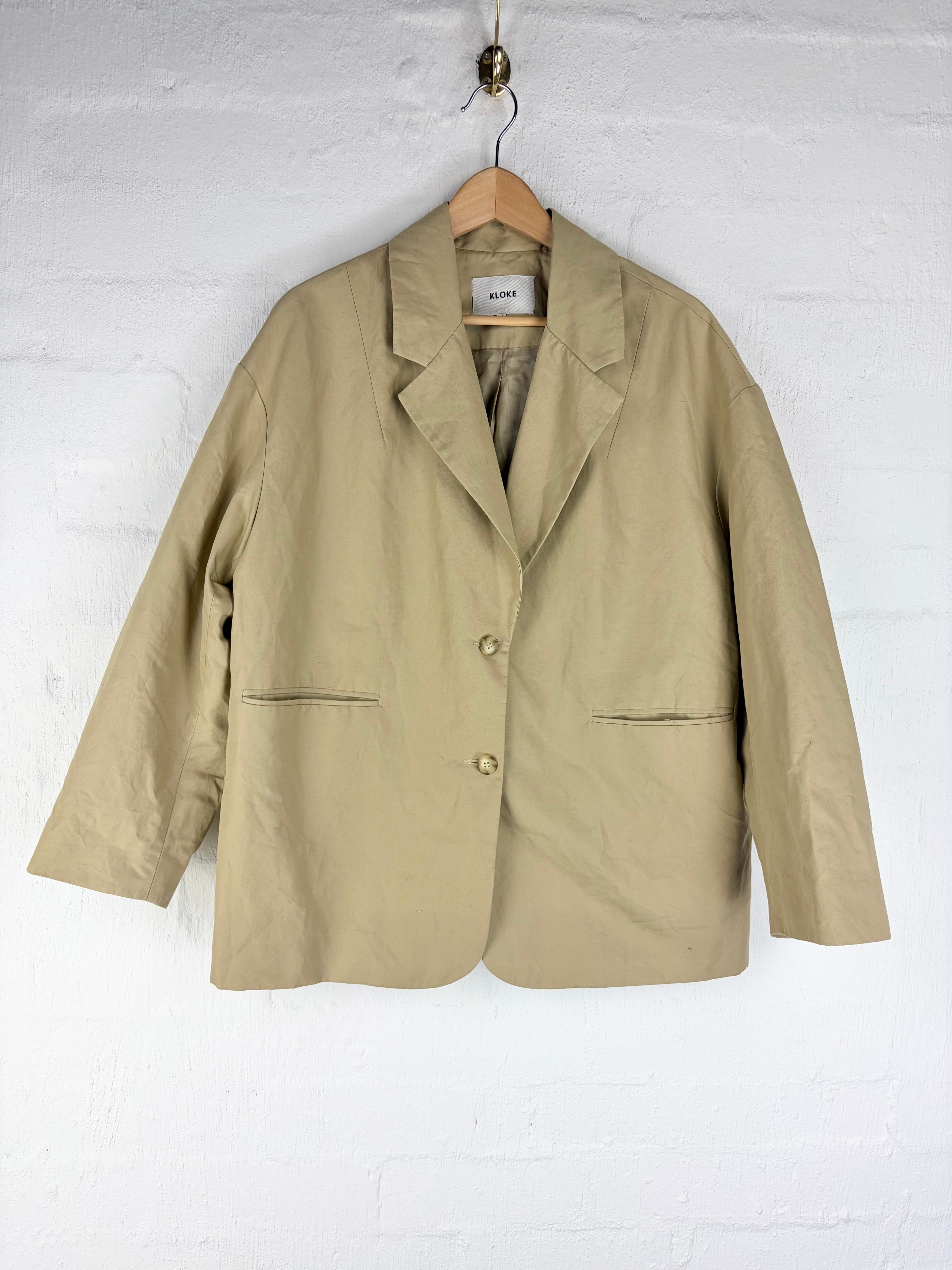 Tan blazer on white brick wall