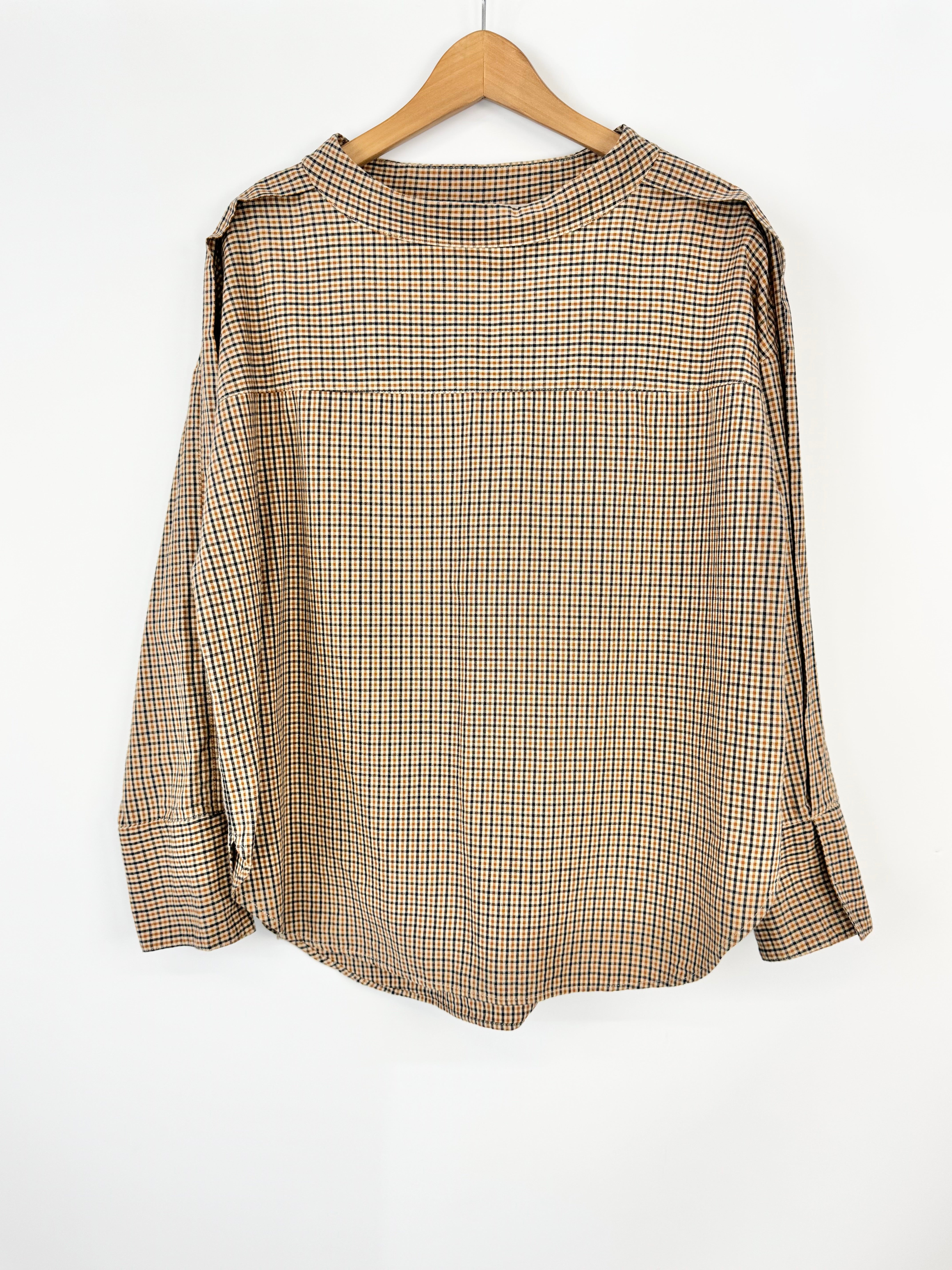 Beige checkered blouse on a wooden hanger against a white background