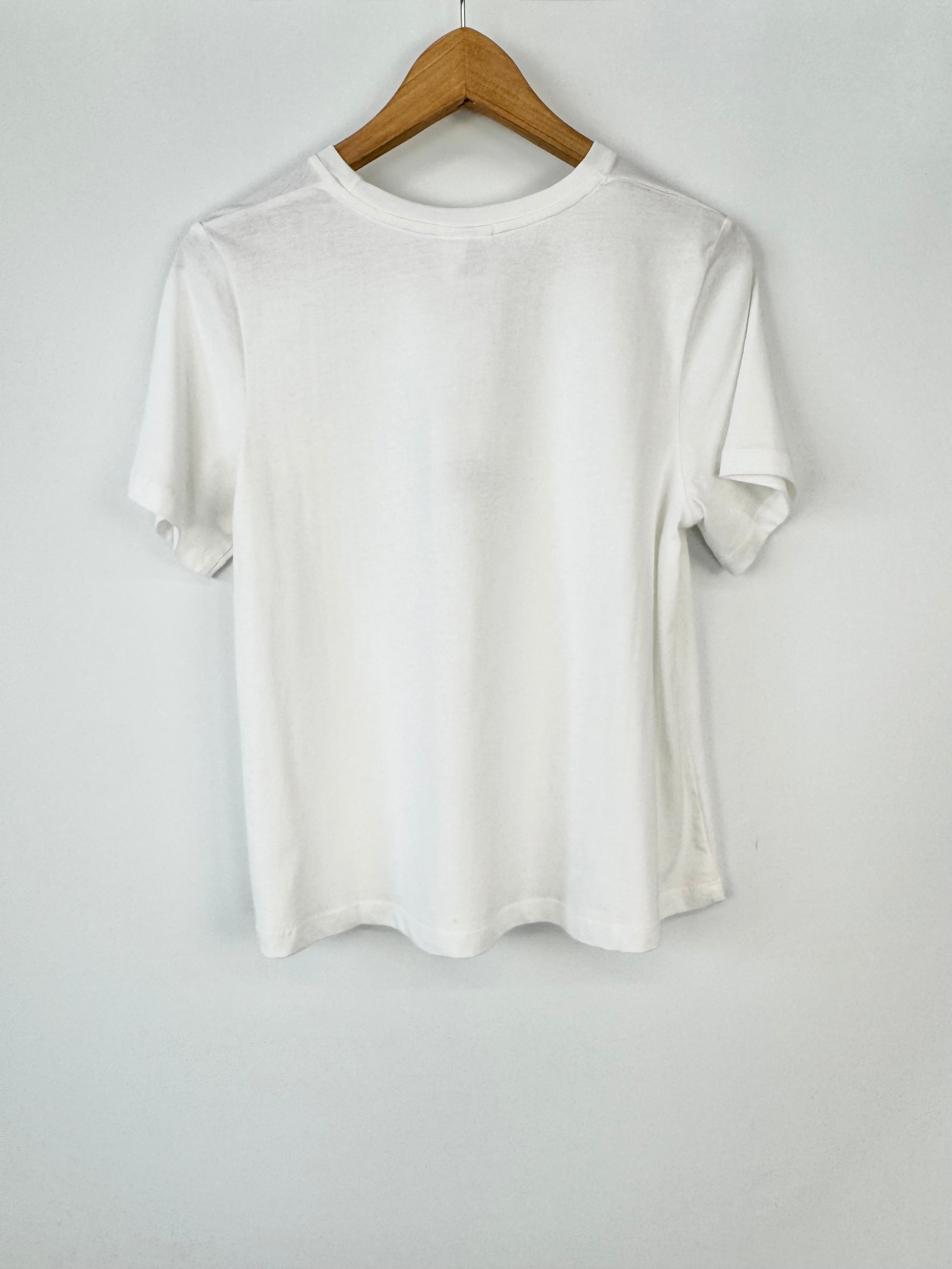 White t-shirt on a wooden hanger against a white background