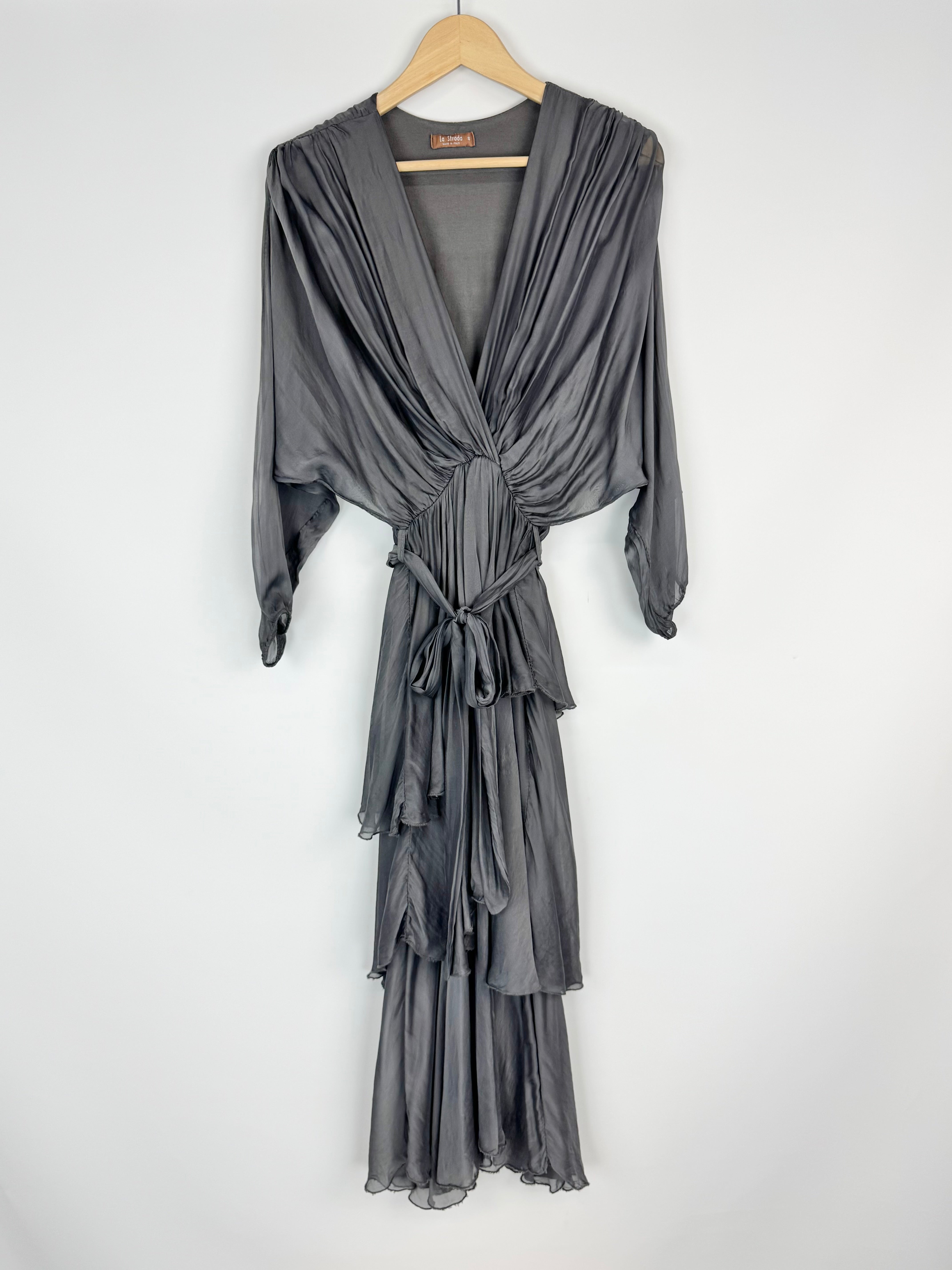 Gray dress with a draped design on a hanger against a white background