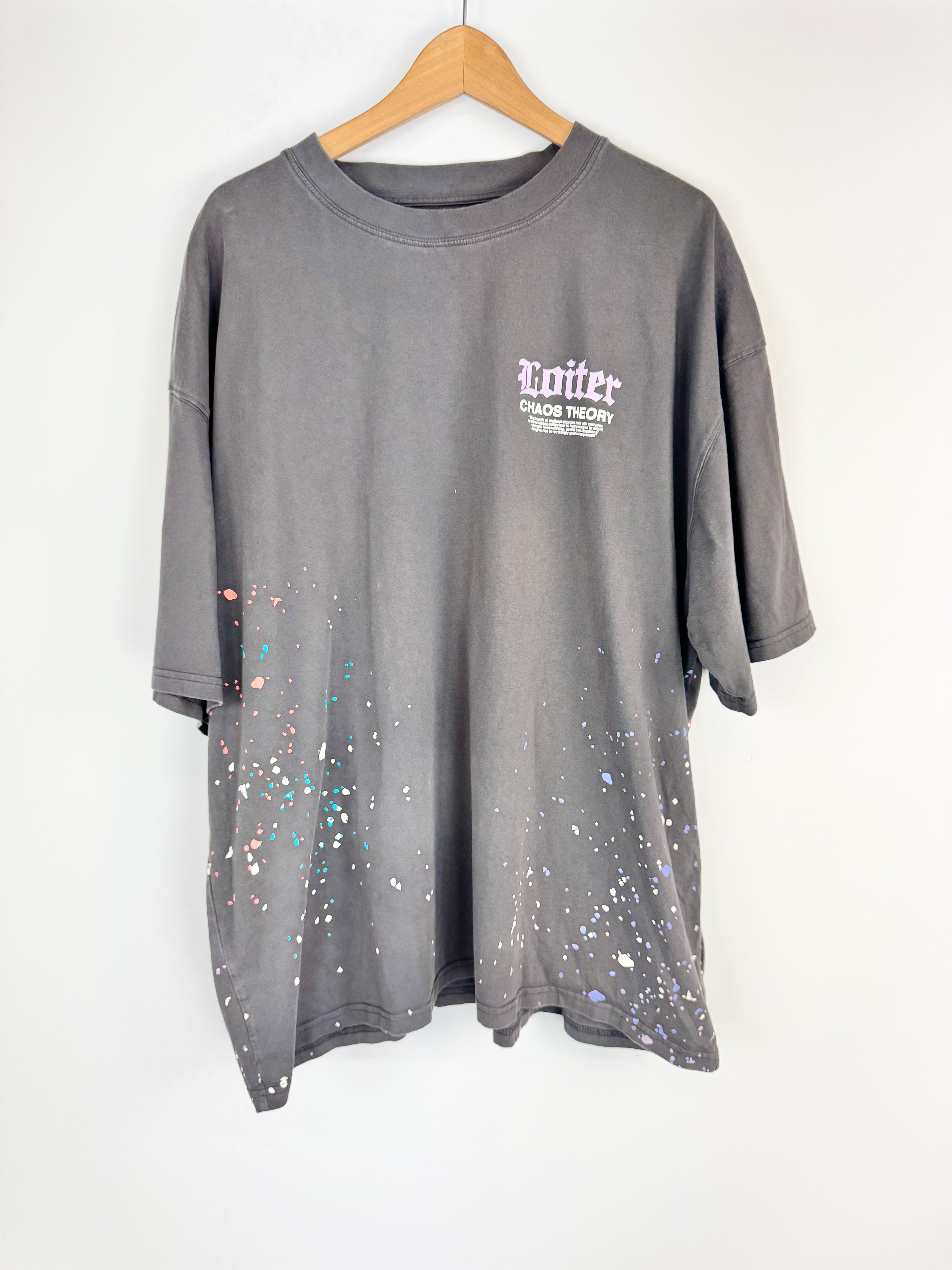 Gray t-shirt with paint splatter design and 'Twitter' logo on a hanger against a white background
