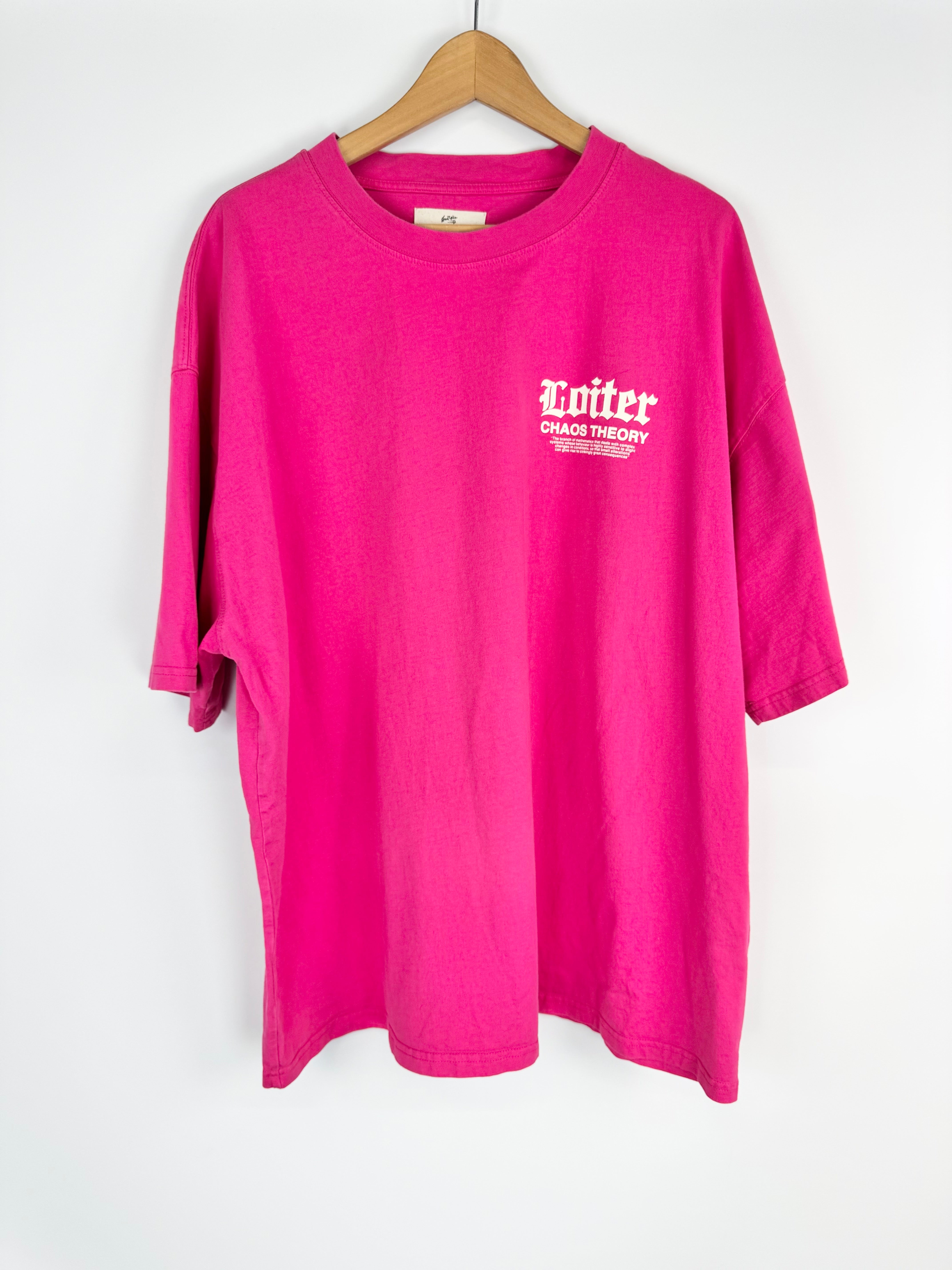 Pink t-shirt with white text on a hanger against a white background
