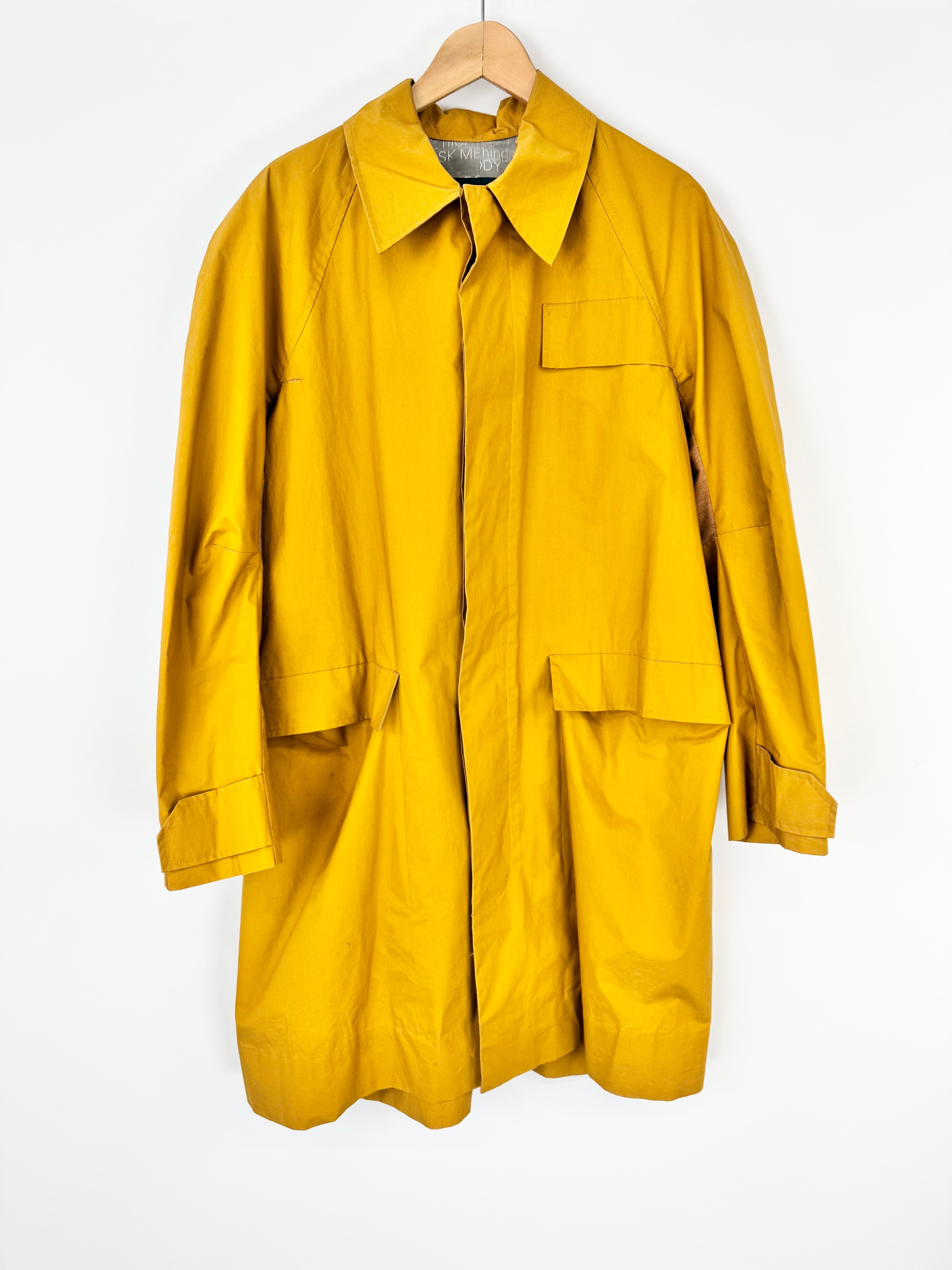 Yellow raincoat on a hanger against a white background