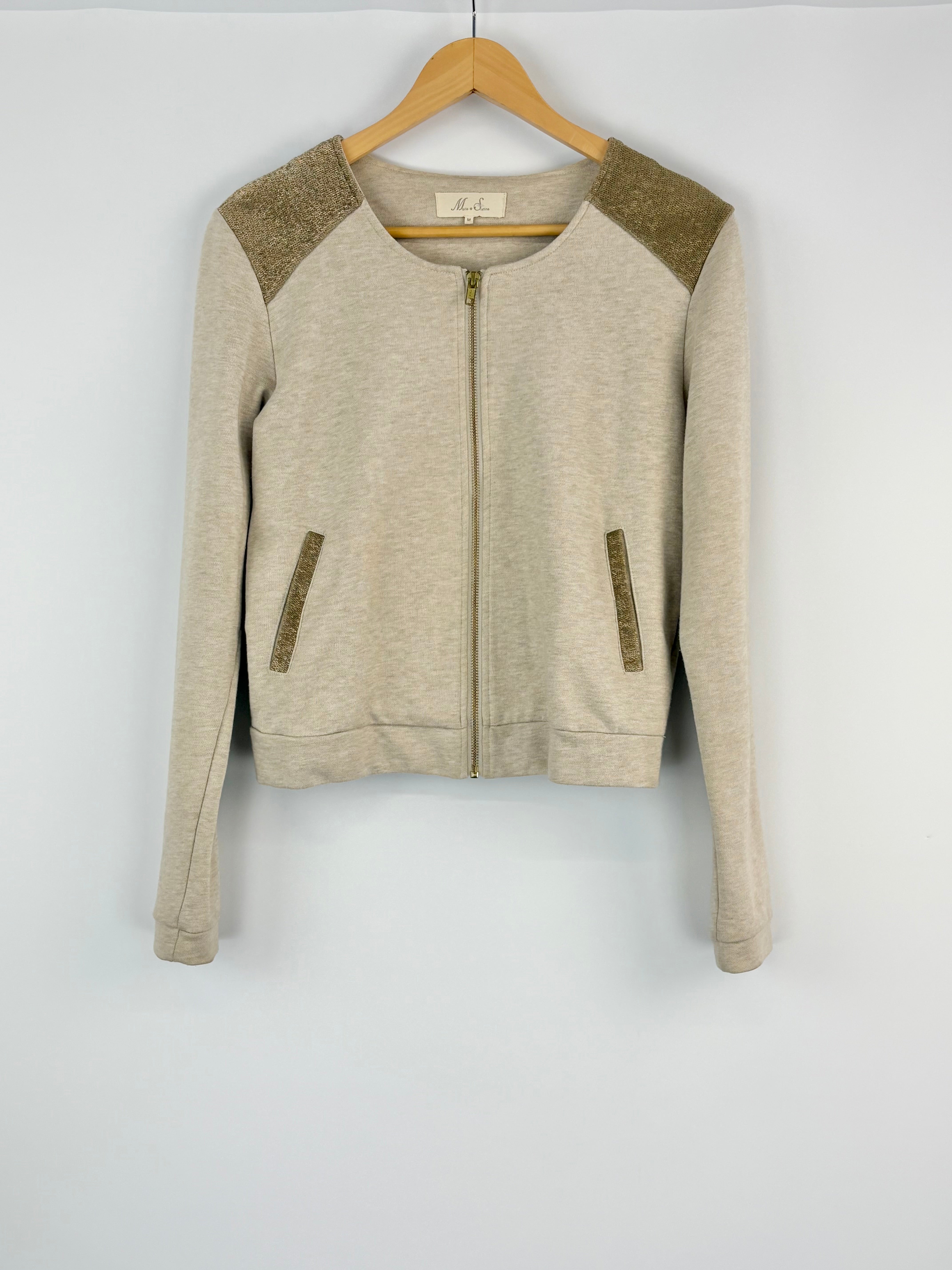 Beige jacket with green accents on a hanger against a white background