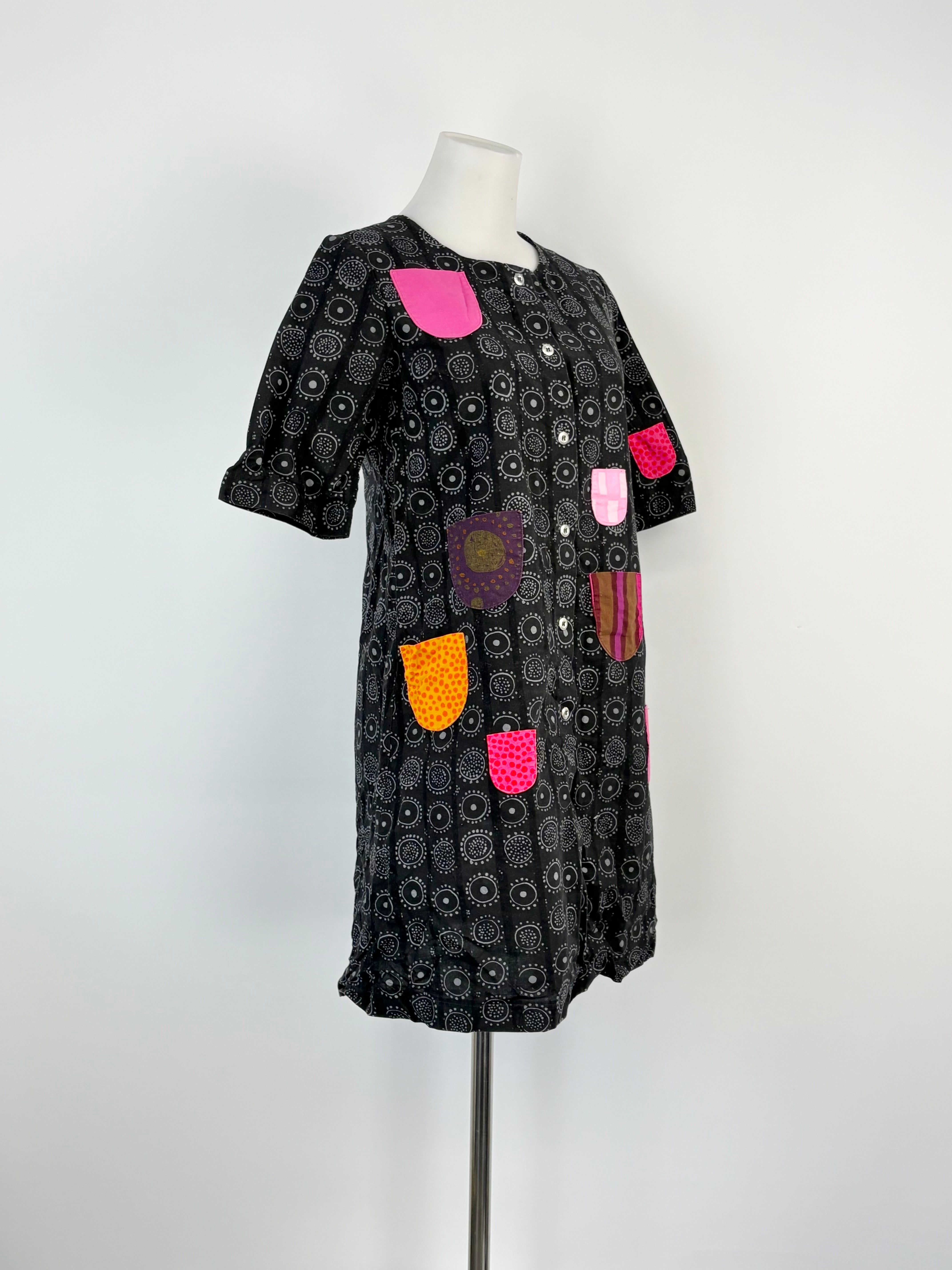 Black patterned dress with colorful patchwork details on a mannequin against a white background.