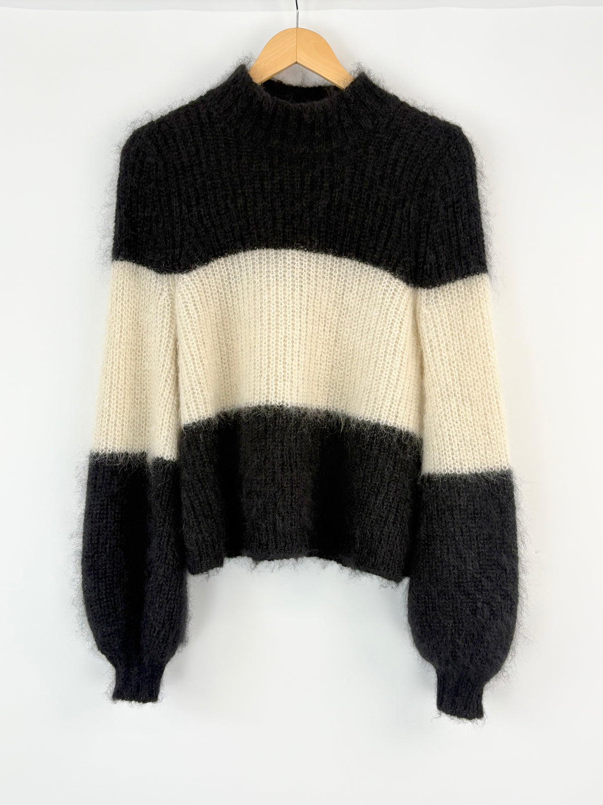 Black and white striped sweater on a hanger against a white background