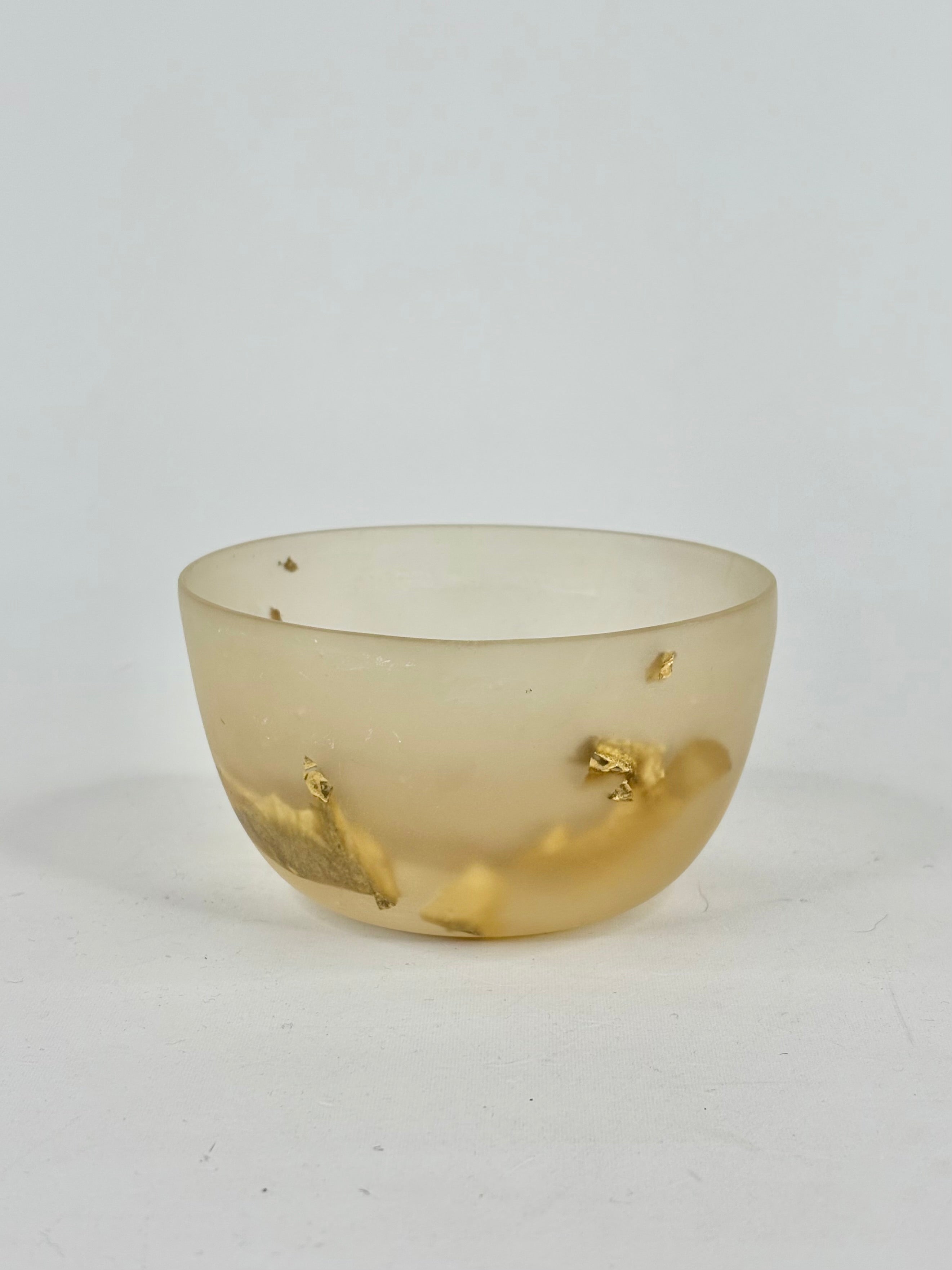 Translucent resin bowl with gold leaf on a white background