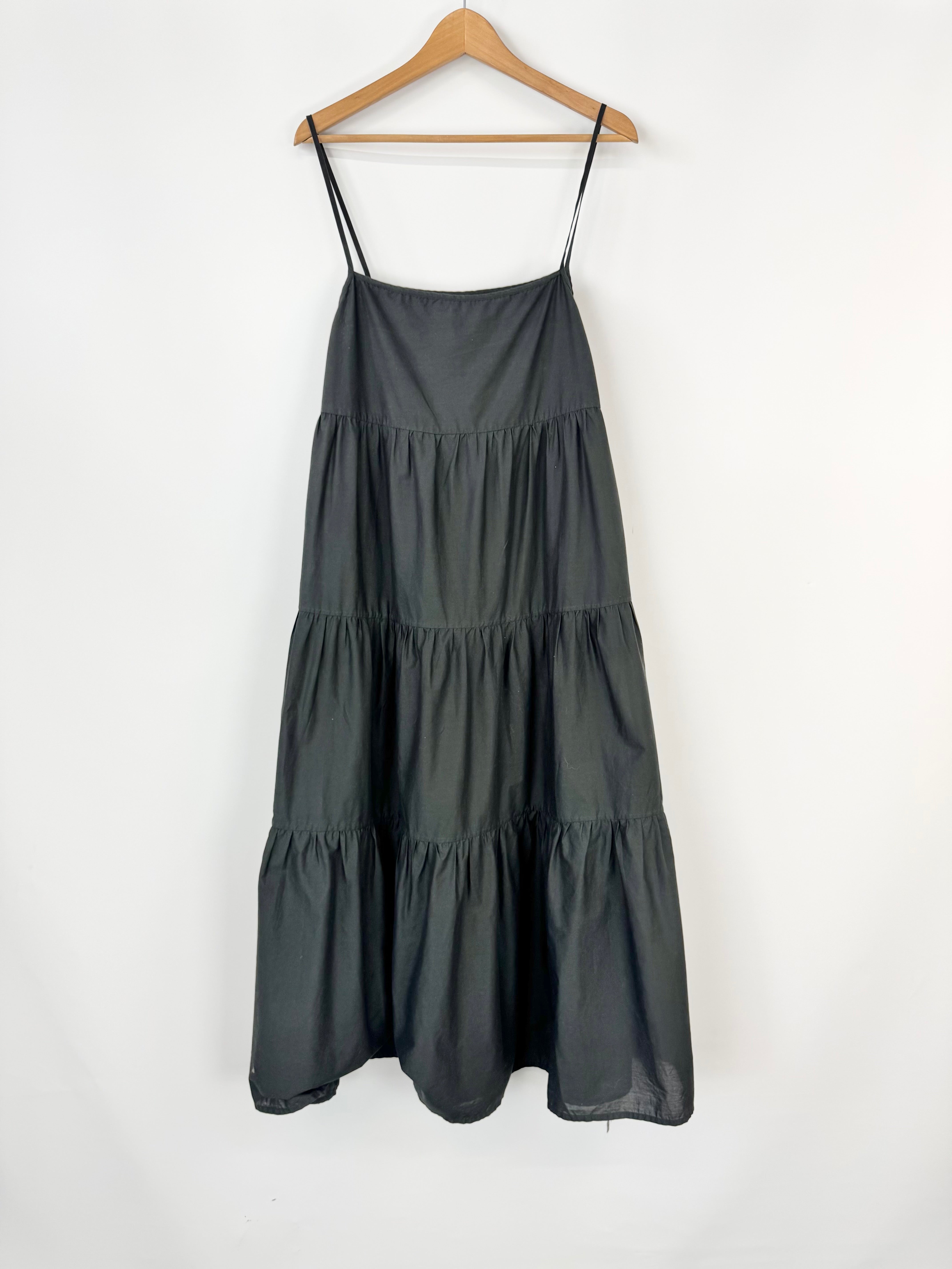 Black tiered dress on a hanger against a white background