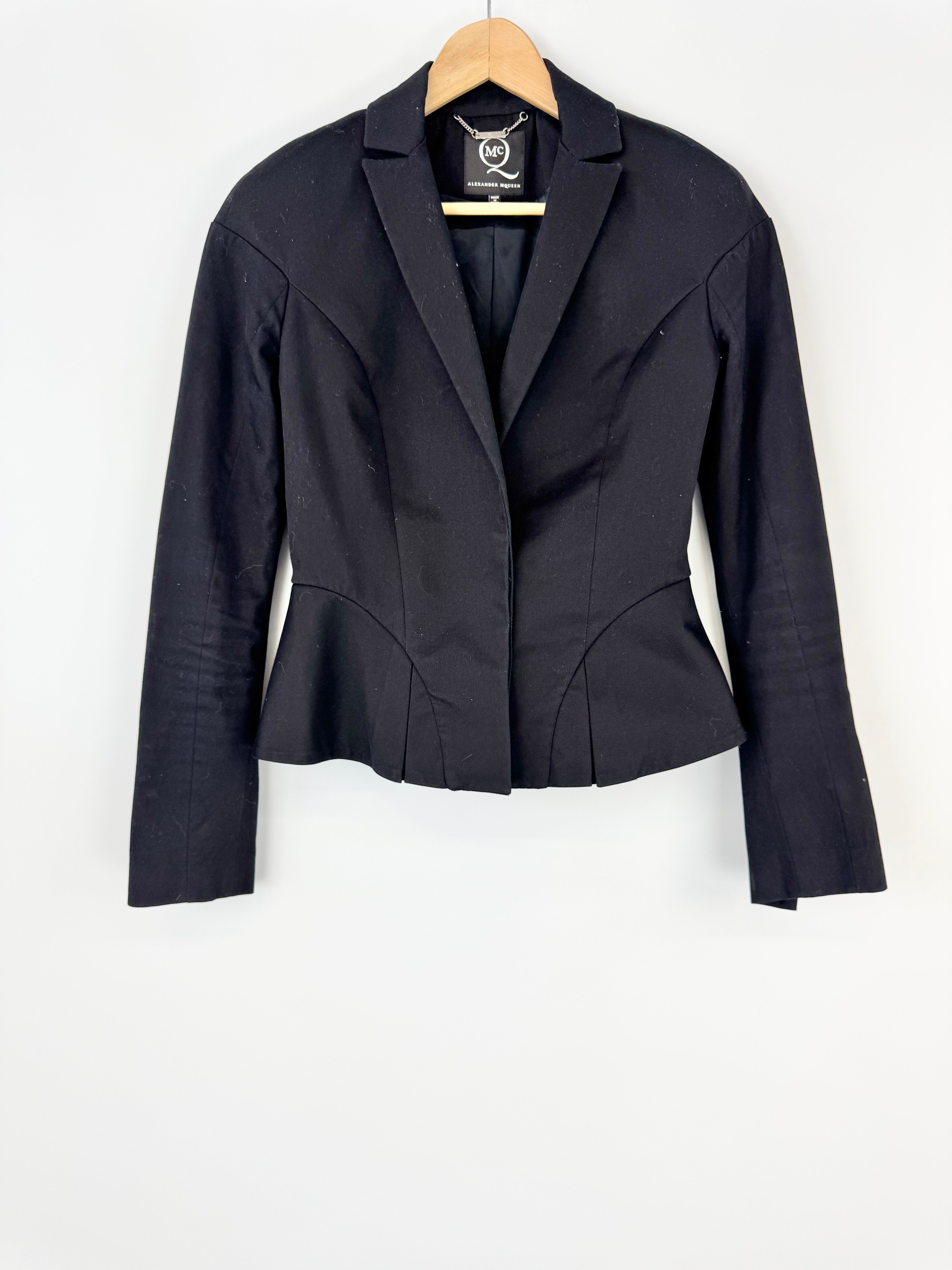 Black blazer on a hanger against a white background