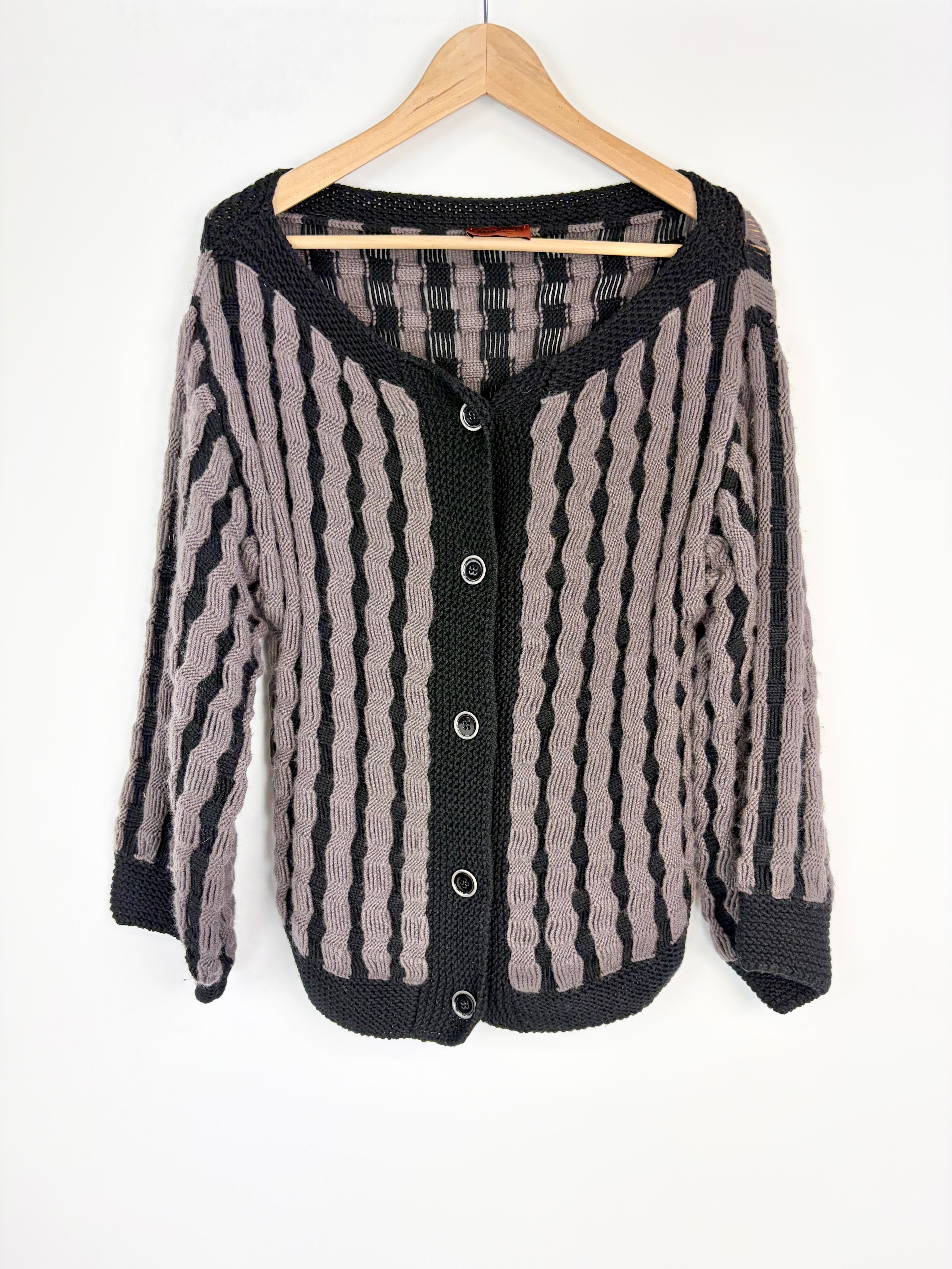 Striped cardigan on a hanger against a white background