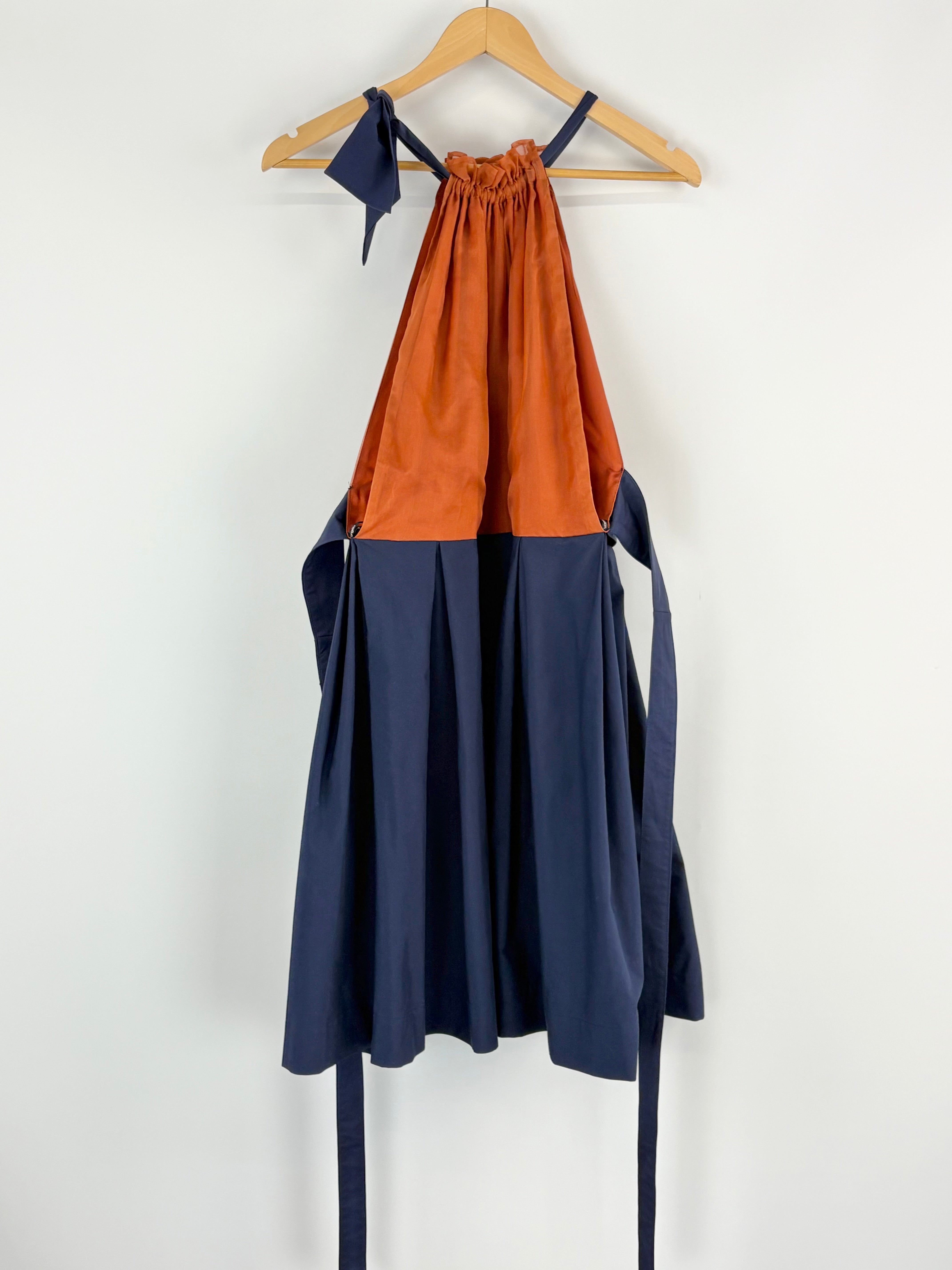 Two-tone dress with rust top and navy bottom on a hanger against a white background