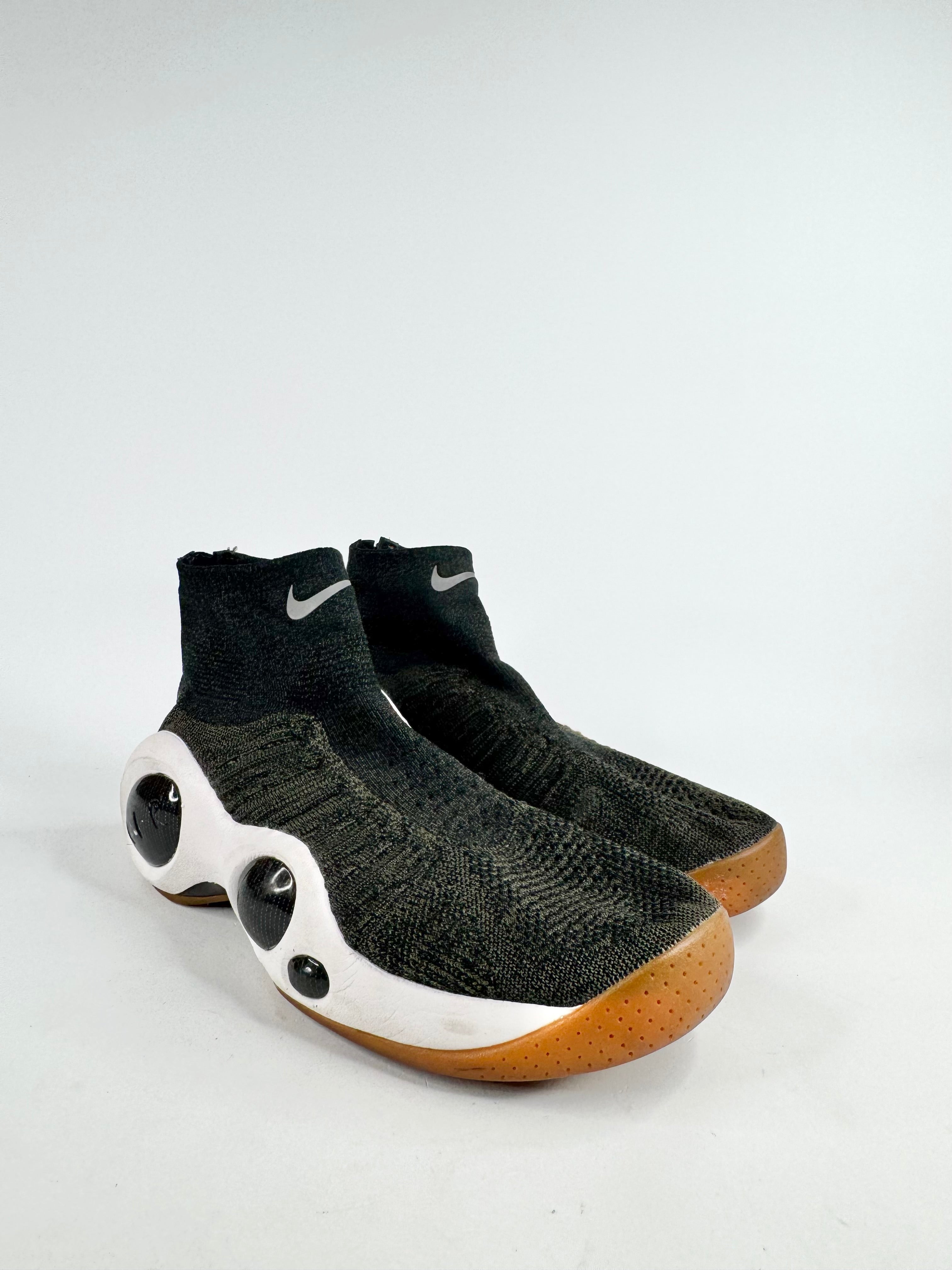 Black and green Nike shoes with white soles on a light gray background
