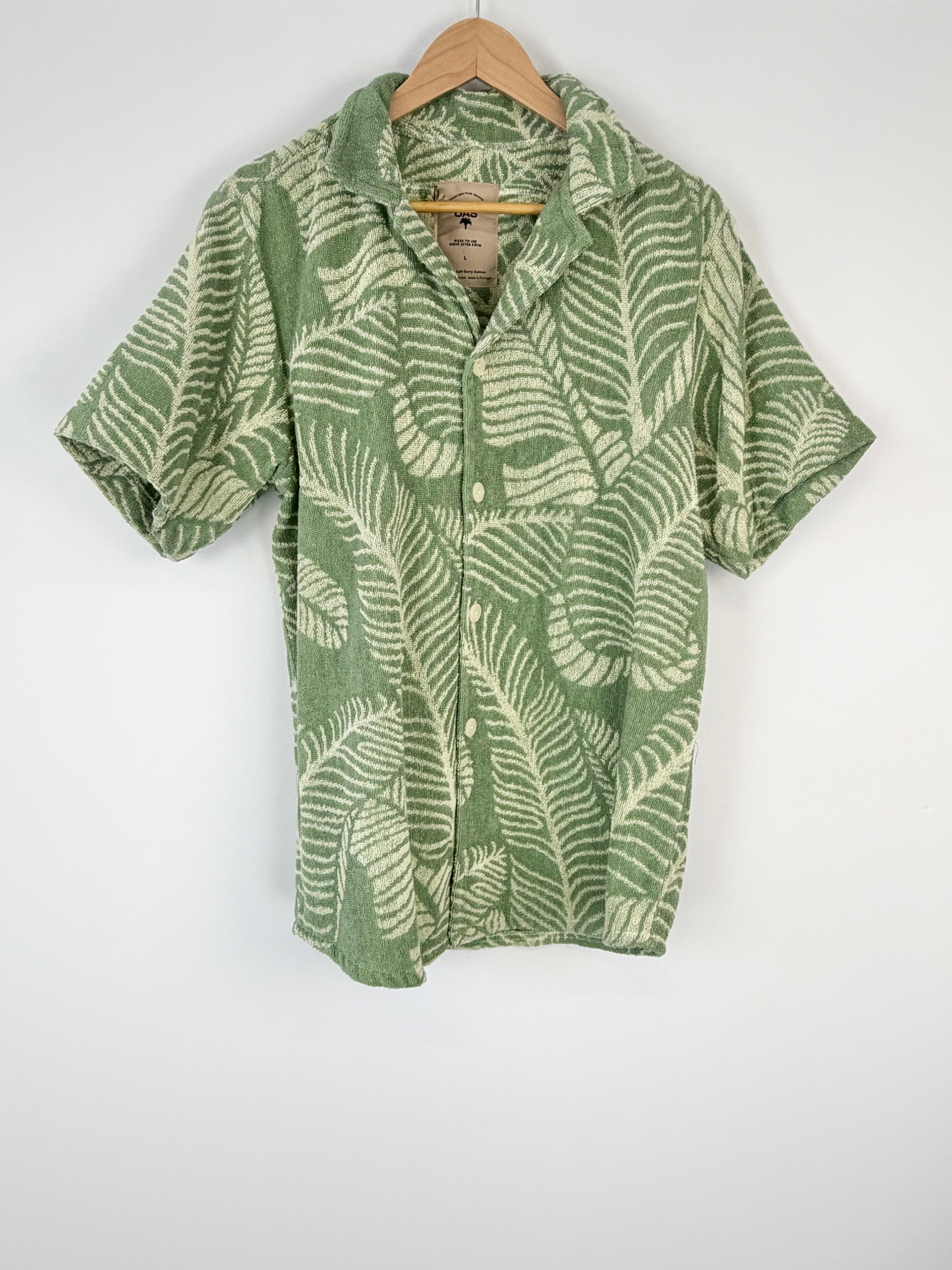 Green and white patterned shirt on a hanger against a white background