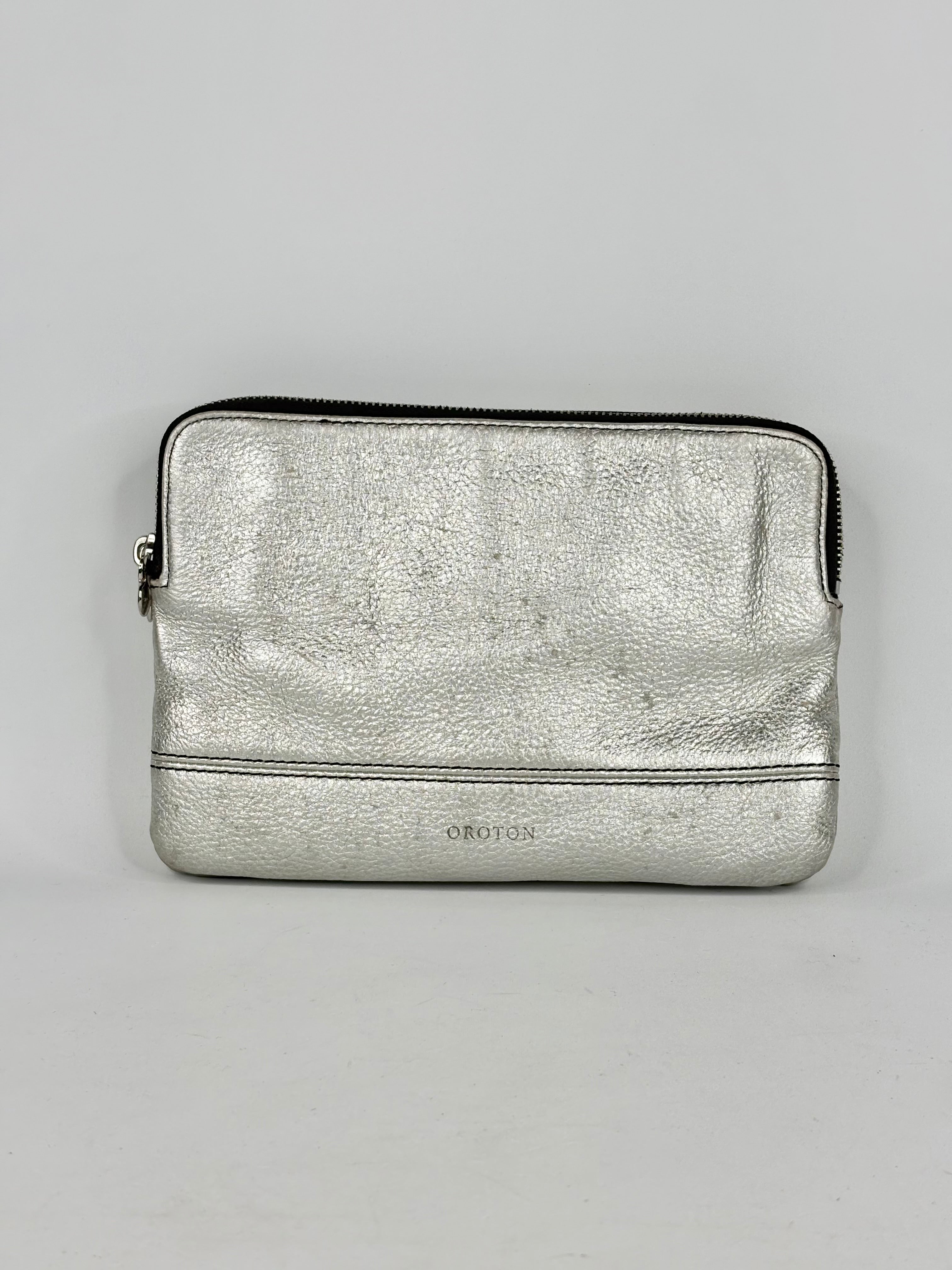Silver metallic pouch with a brand logo on a gray background
