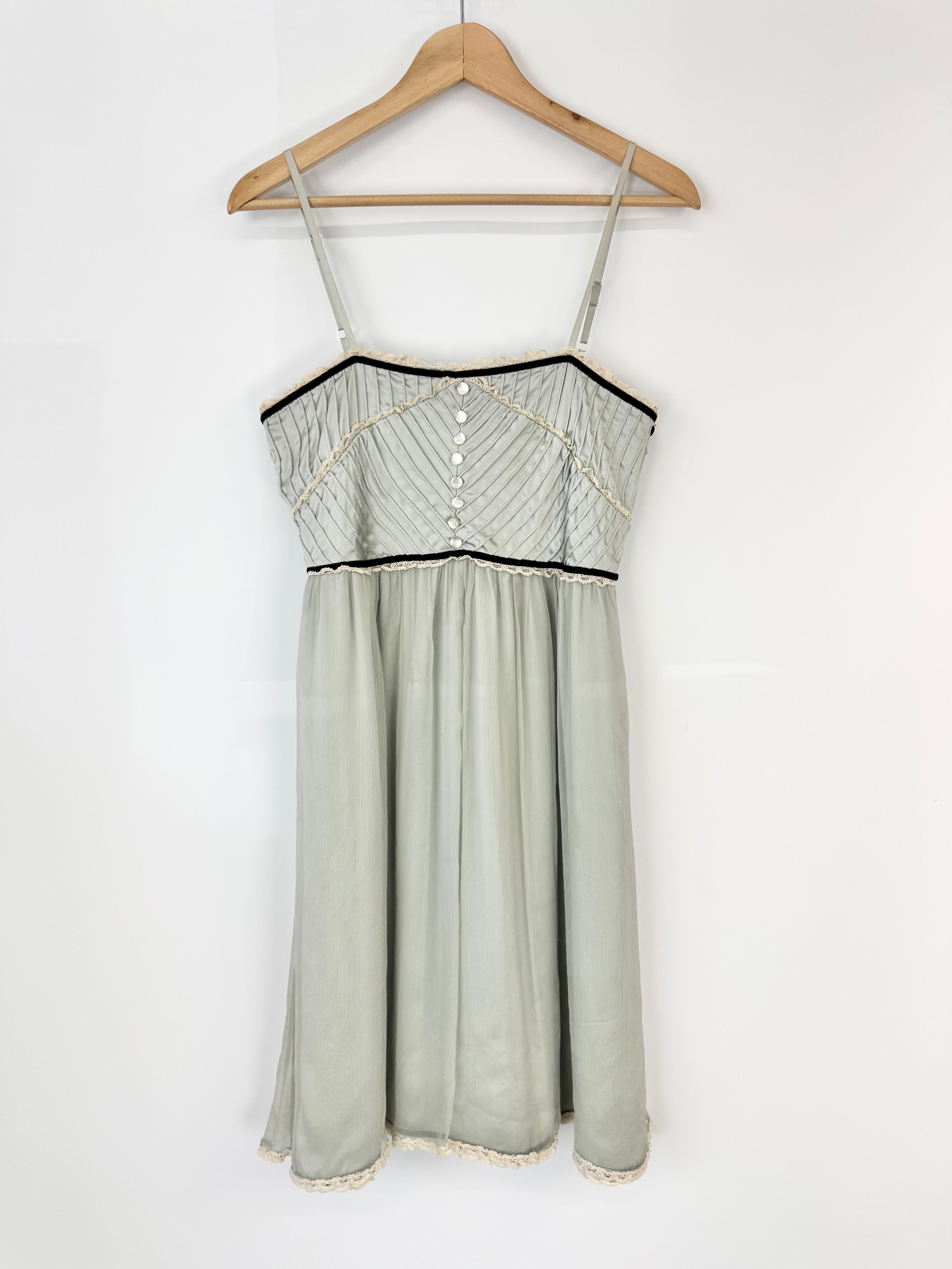 Light green dress with black trim on a wooden hanger against a white background