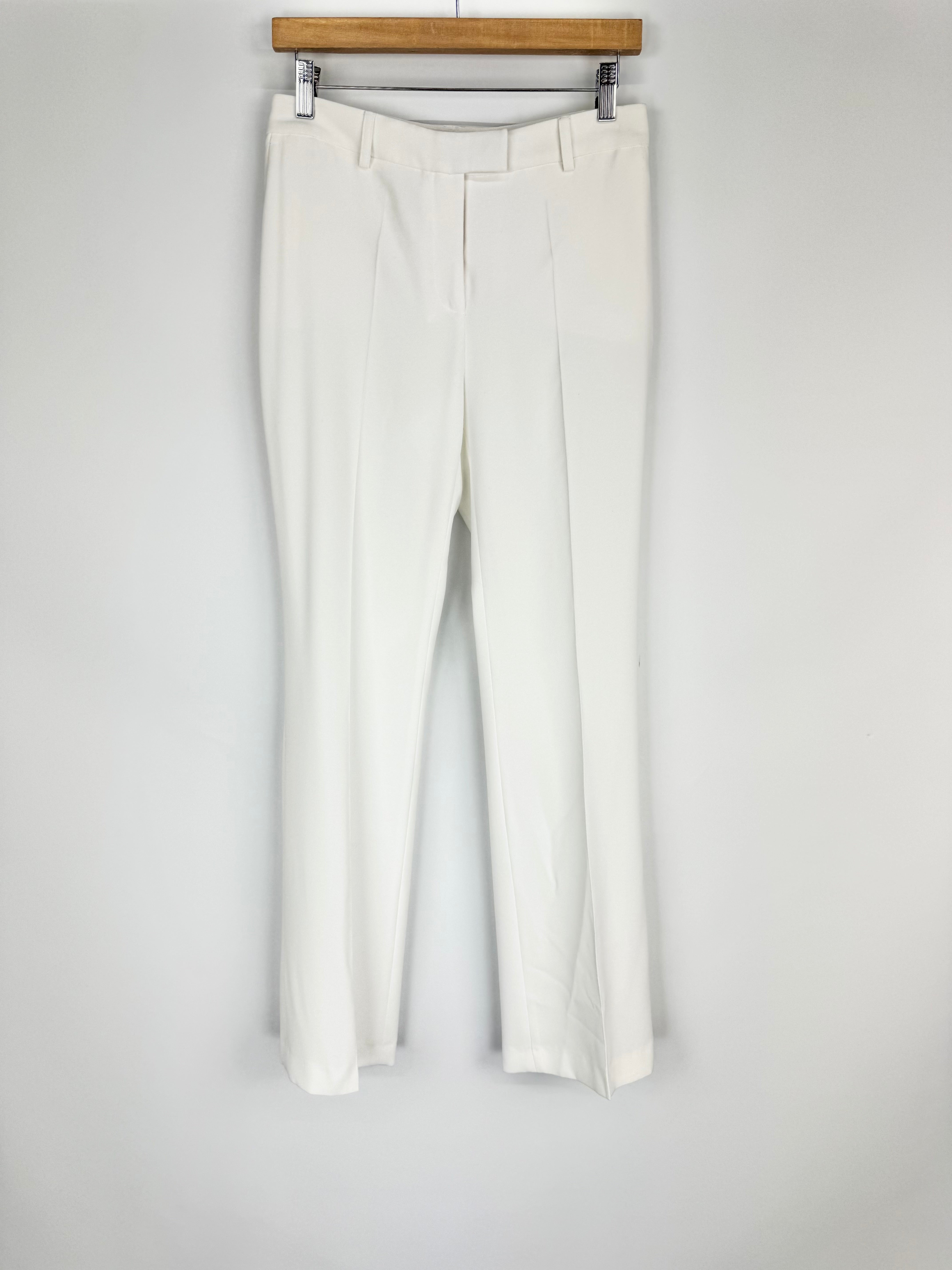 White pants hanging on a wooden hanger against a white background