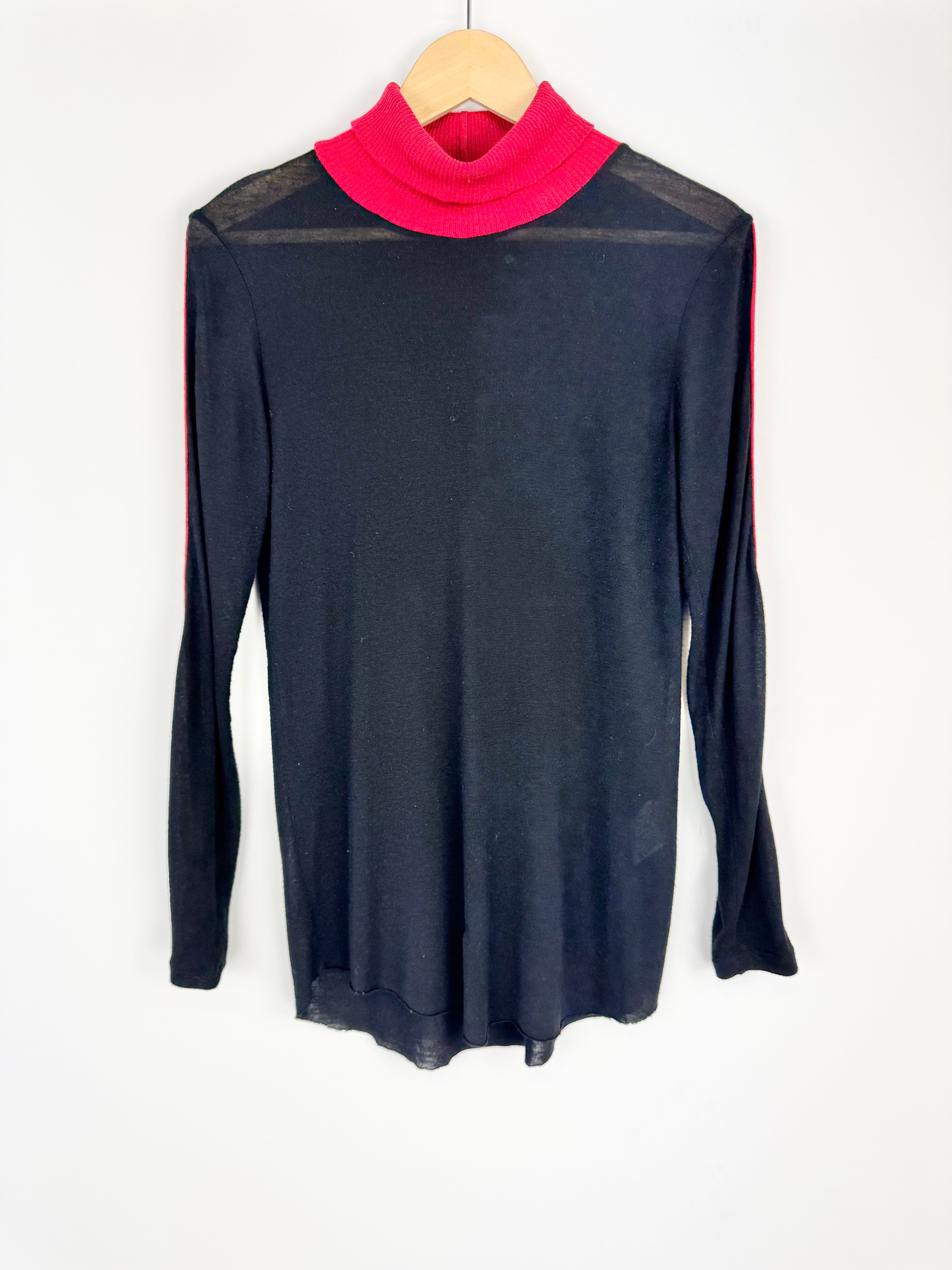 Black long-sleeve top with pink turtleneck on a hanger against a white background