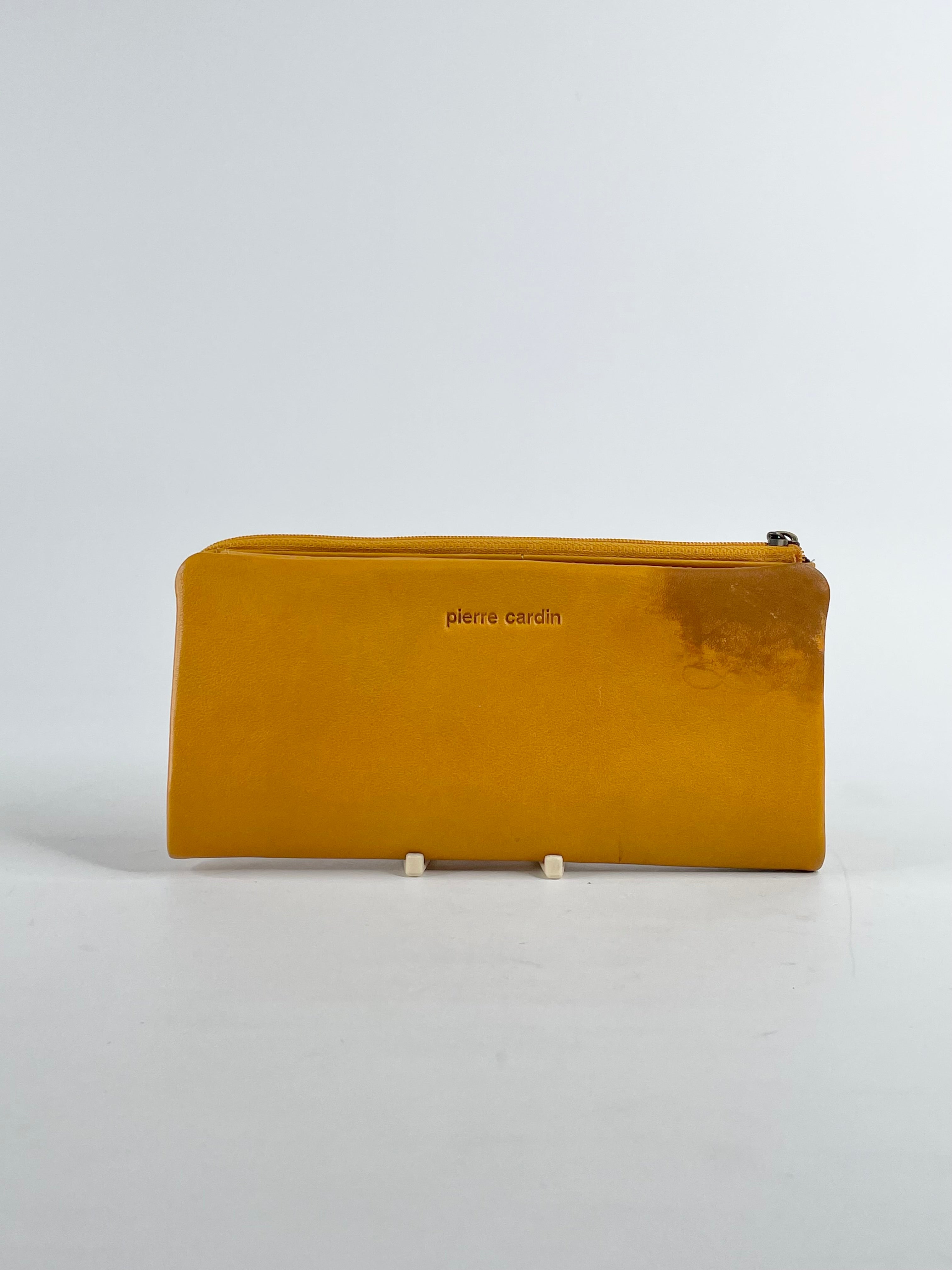 A mustard yellow leather wallet with the brand name 'Pierre Cardin' visible on the front.