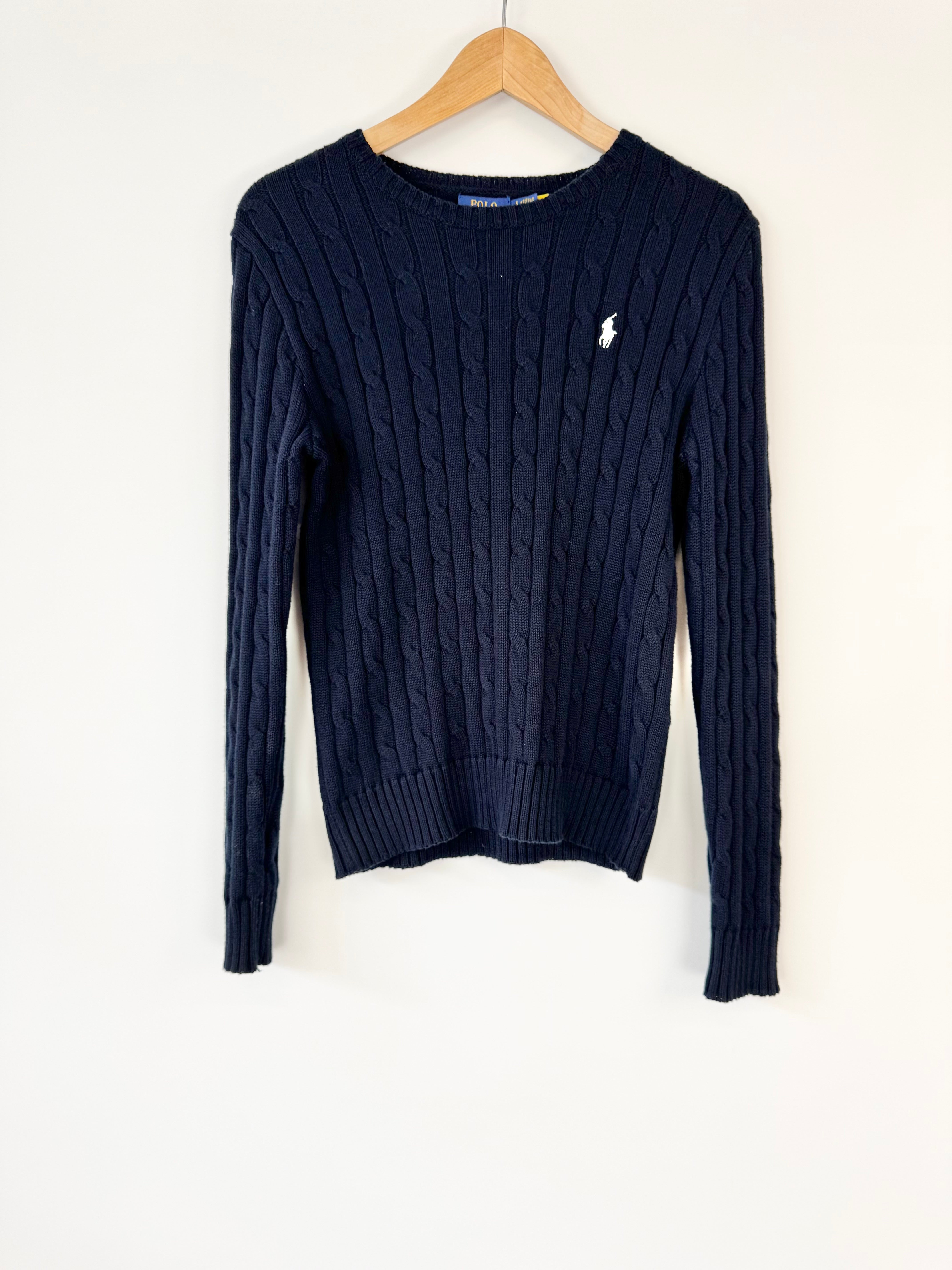 Navy blue sweater with a brand logo on a wooden hanger against a white background
