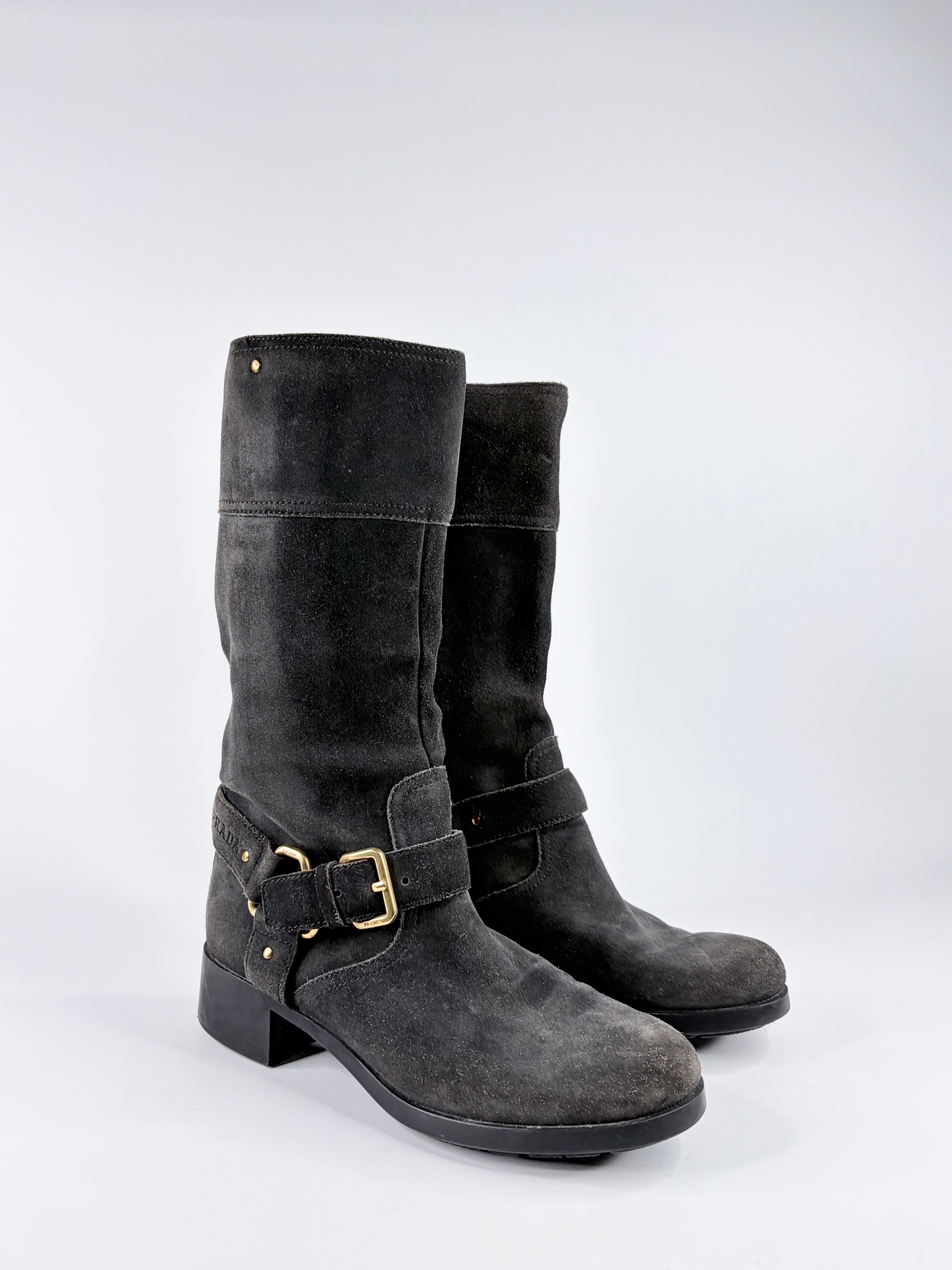 Pair of gray suede knee-high boots with gold buckles on a white background