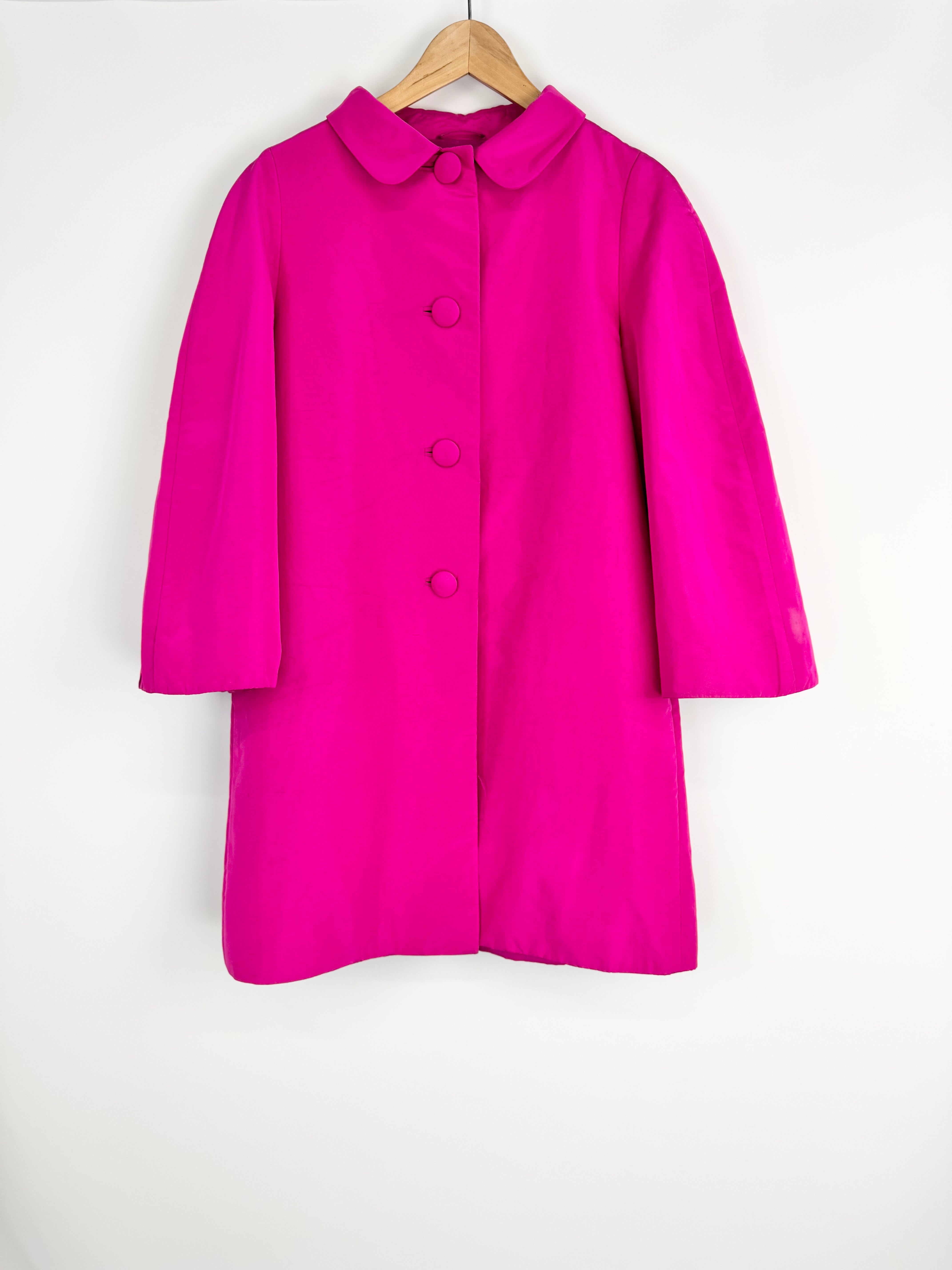 Pink coat on a hanger against a white background