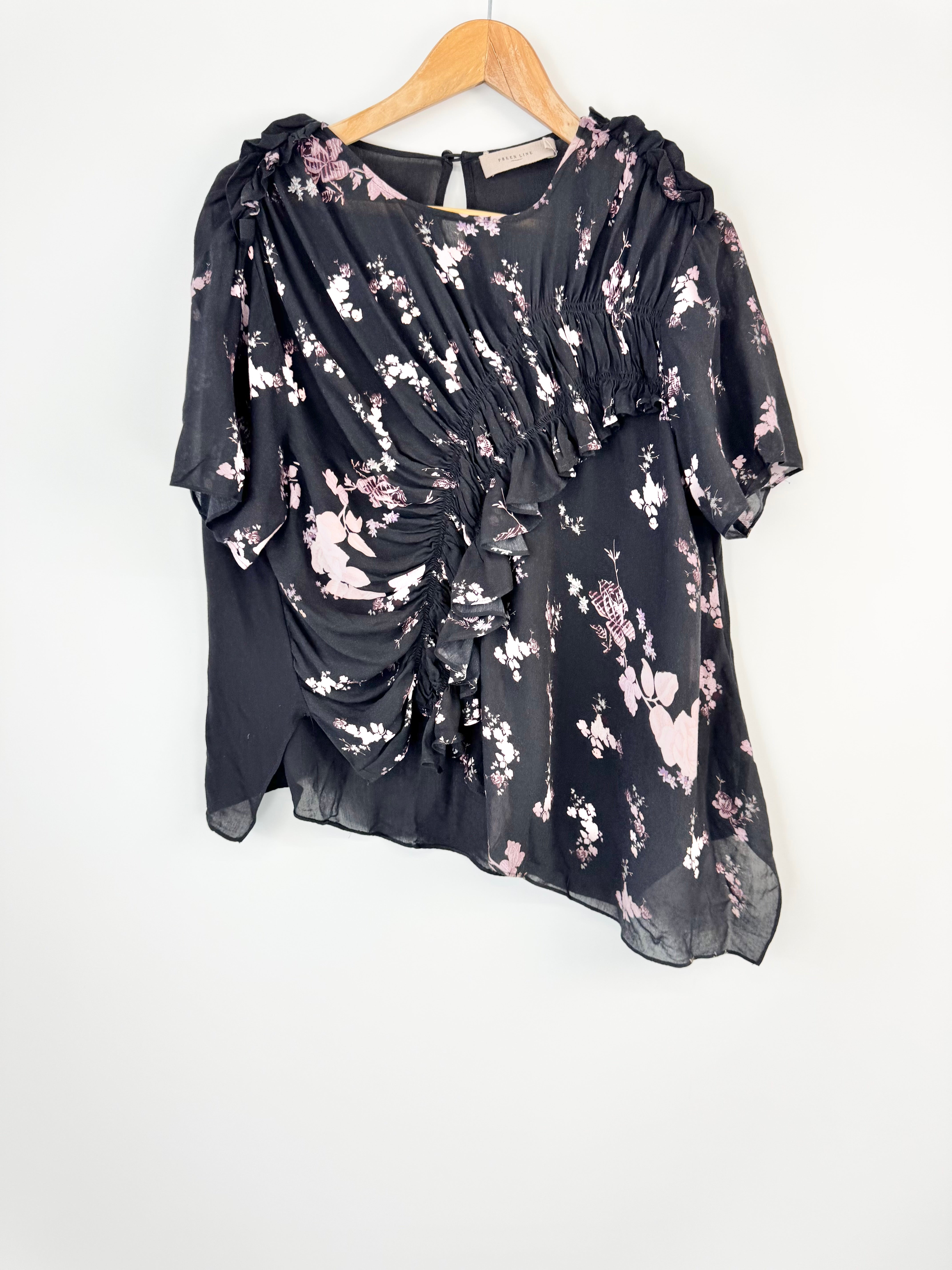 Black floral blouse on a hanger against a white background